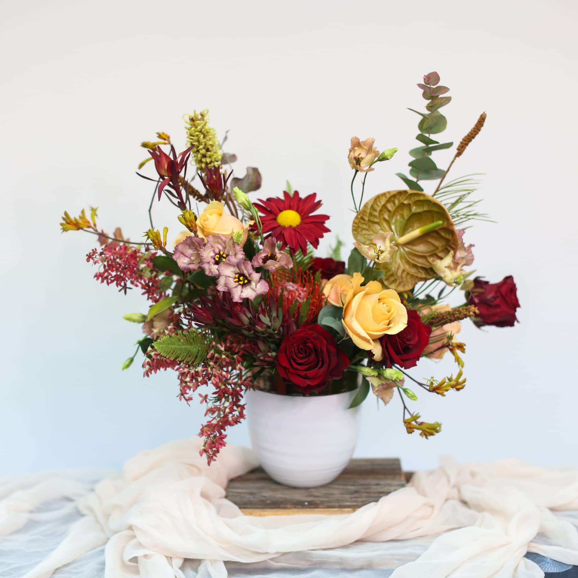 Mixed bouquet of red and yellow flowers in a white vase