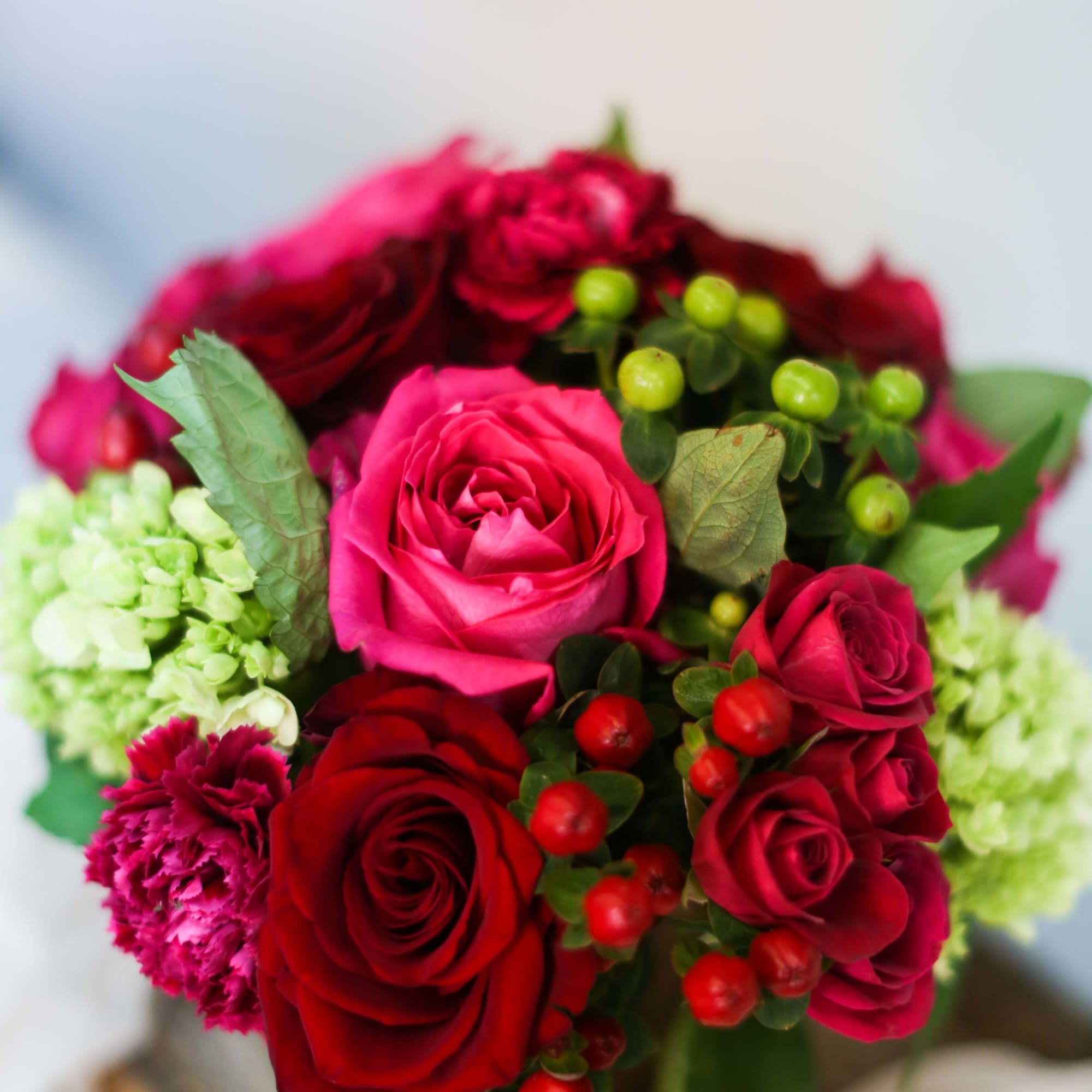 Bouquet of red and pink roses with green berries and carnations