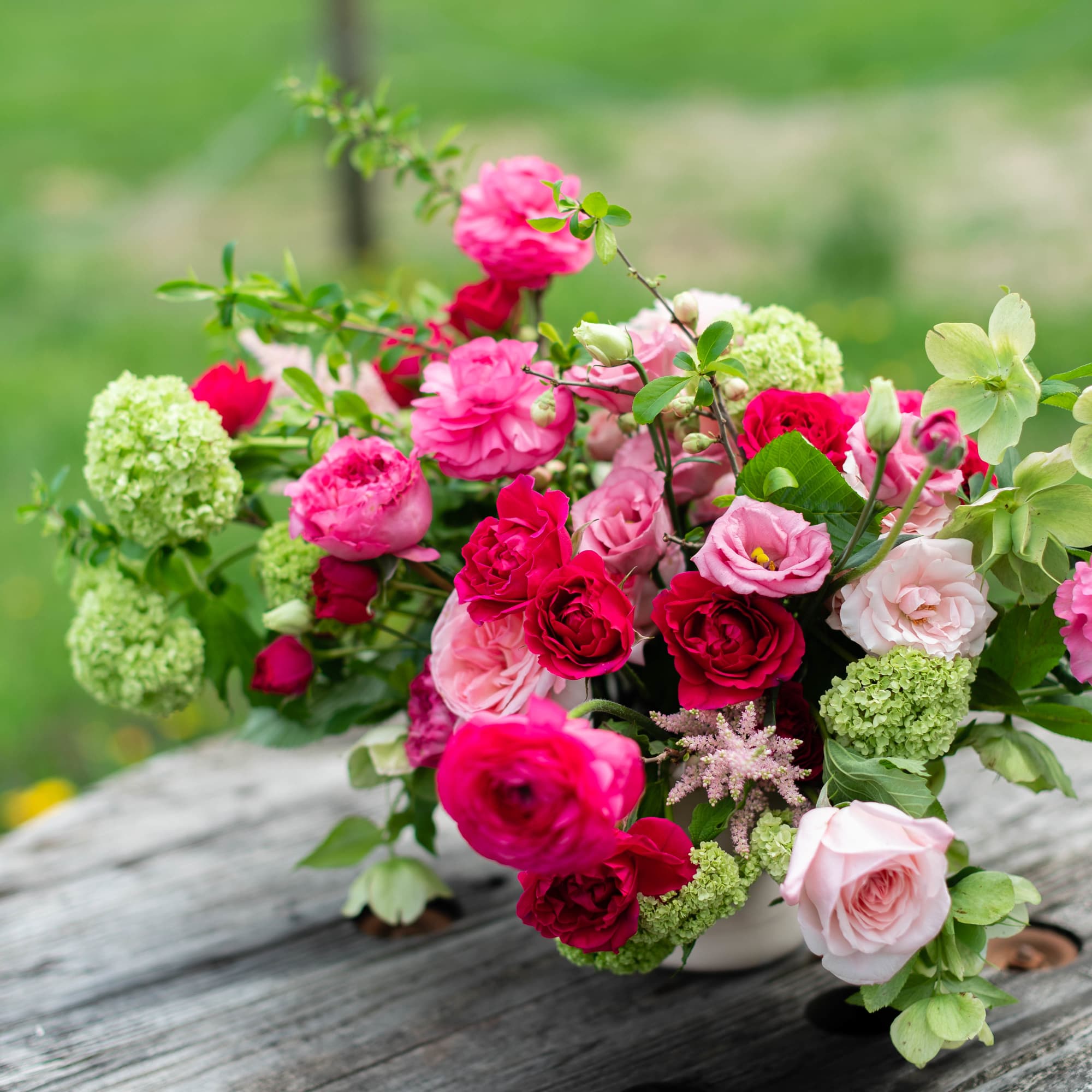 Bouquet of pink and red roses with green blooms in a low vase