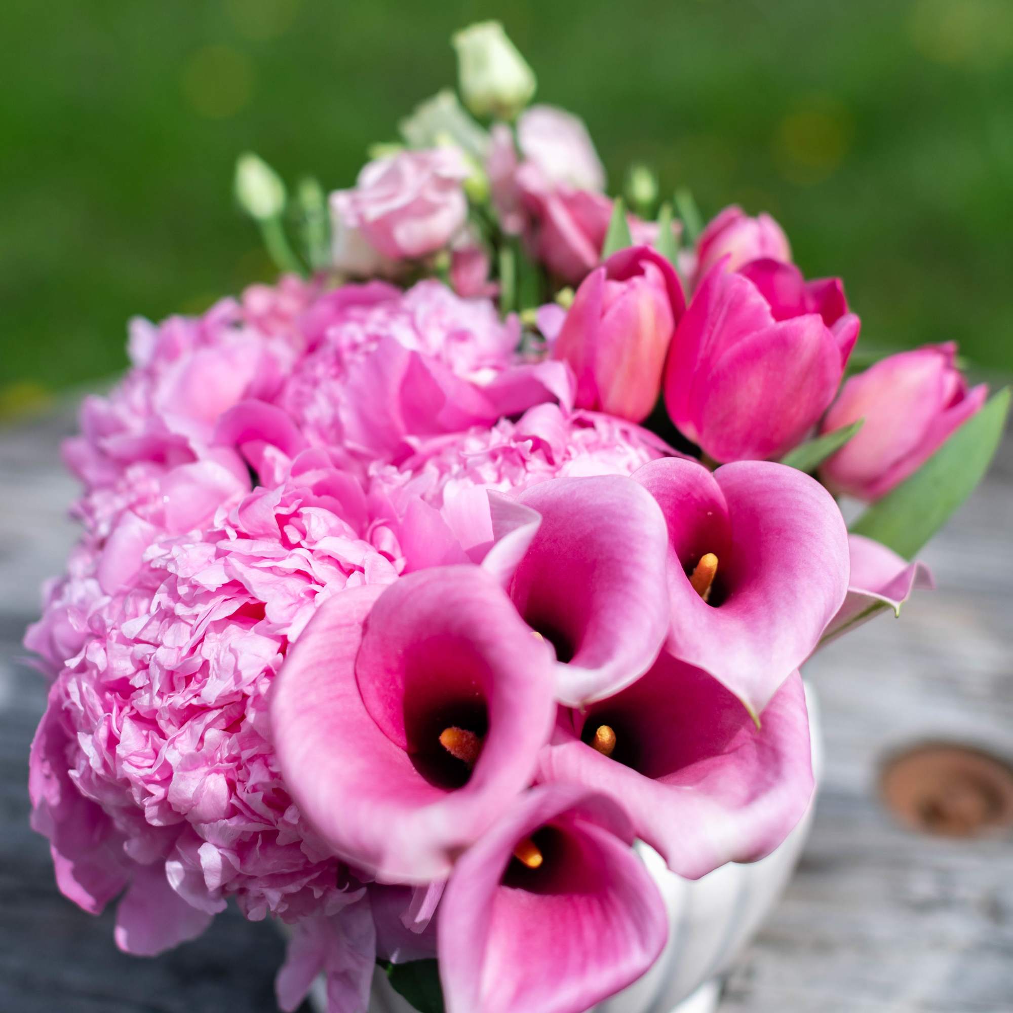 Pink calla lilies and peonies in a white vase