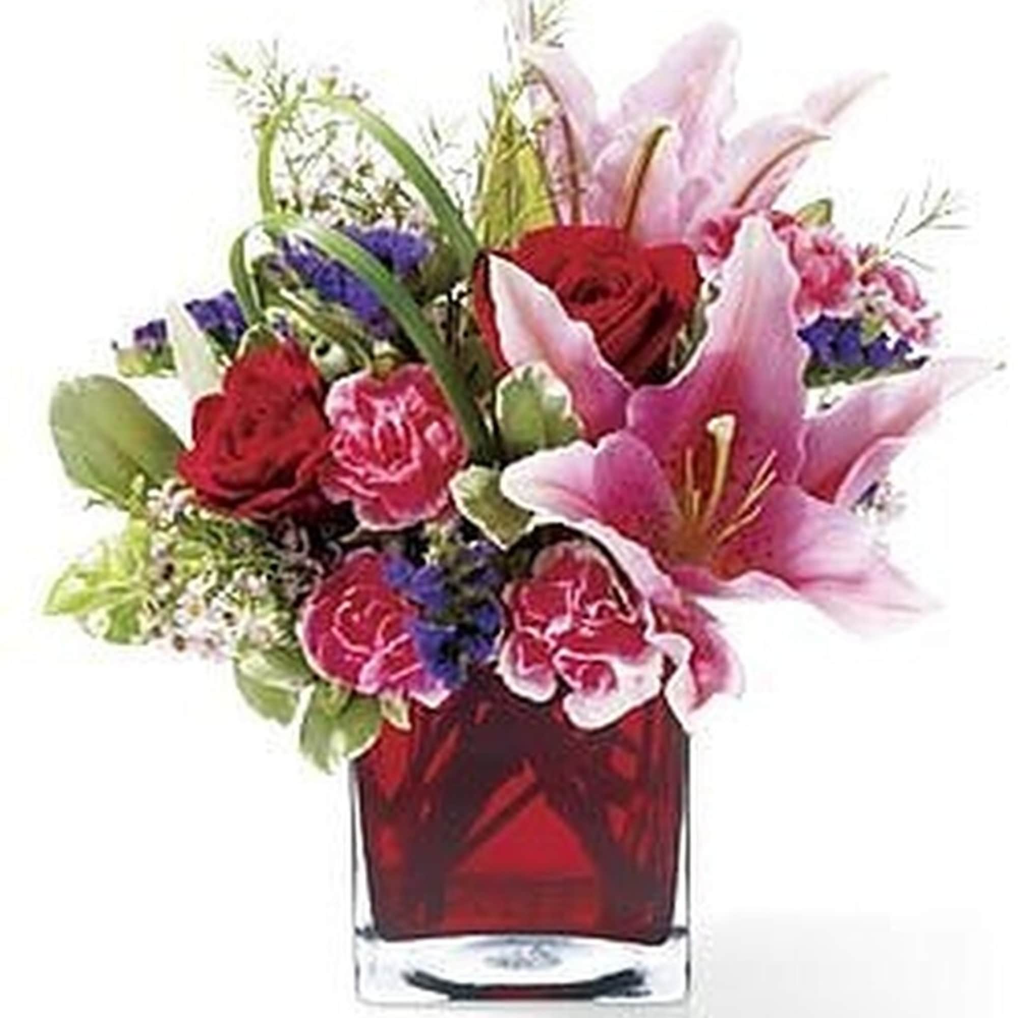 Pink lilies, red roses, and pink carnations arranged in a red glass cube vase