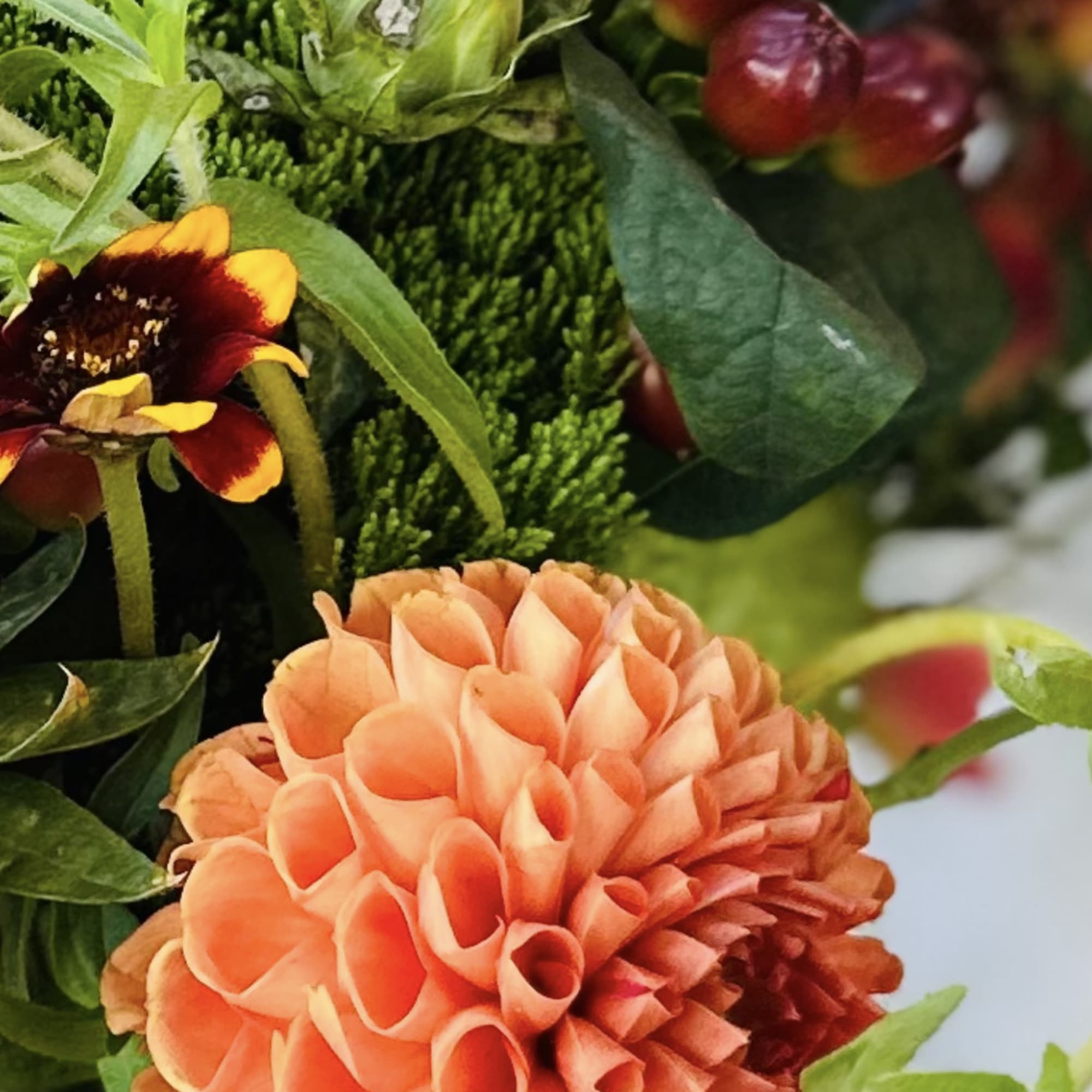 Orange dahlia with green and burgundy flowers in a mixed bouquet