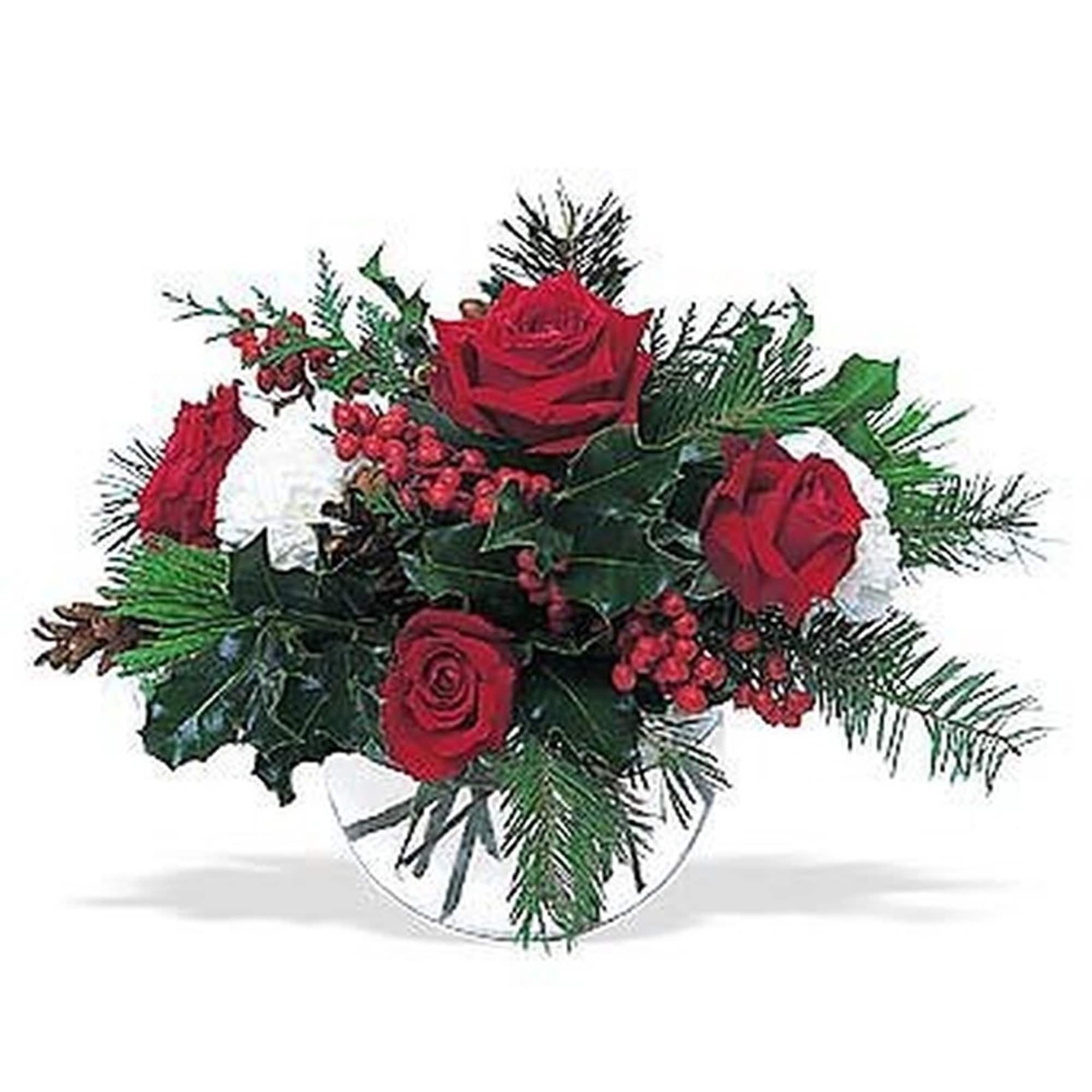 Low arrangement of red roses, white flowers, and red berries with evergreens in a clear glass bowl vase