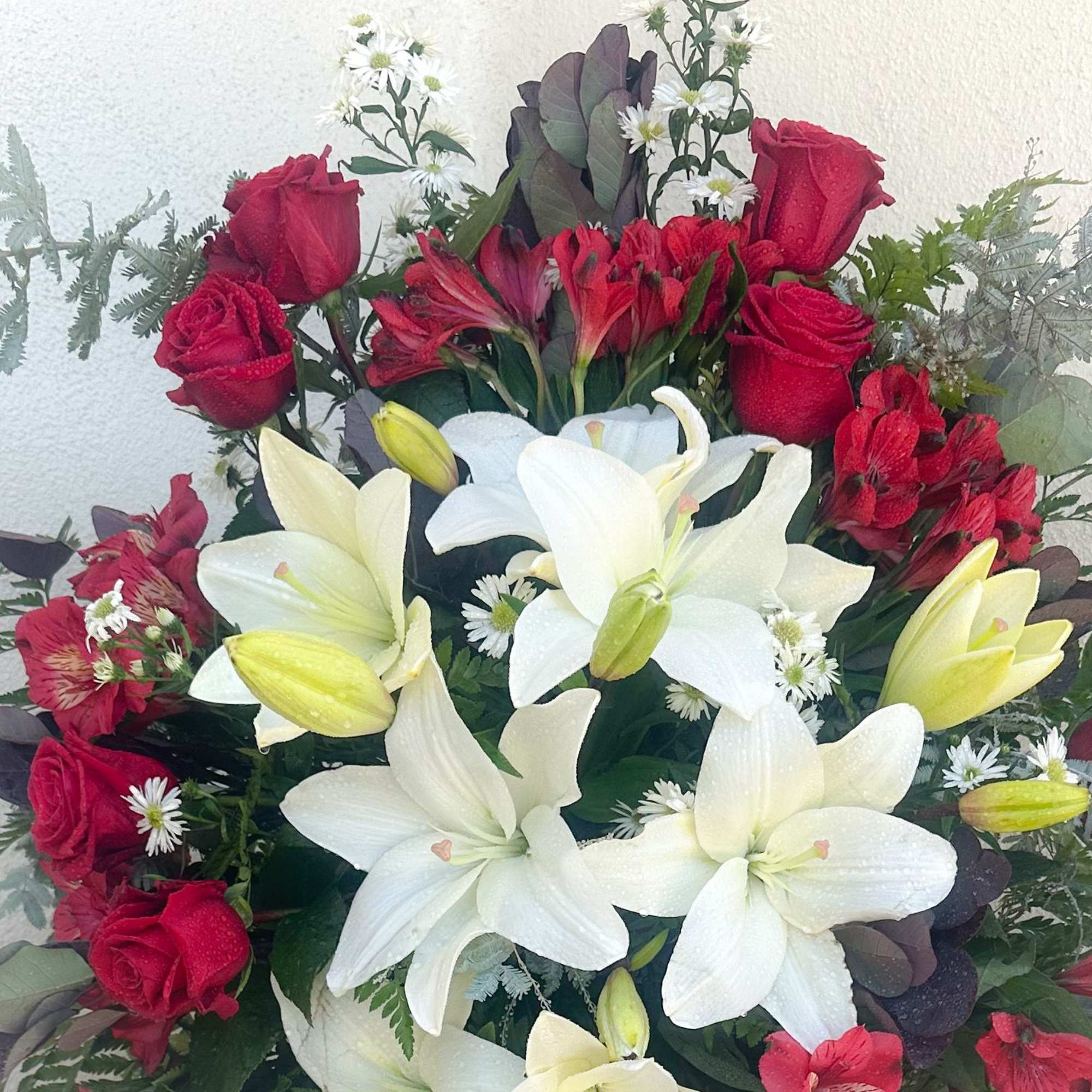 Bouquet of red roses and white lilies with small white daisies
