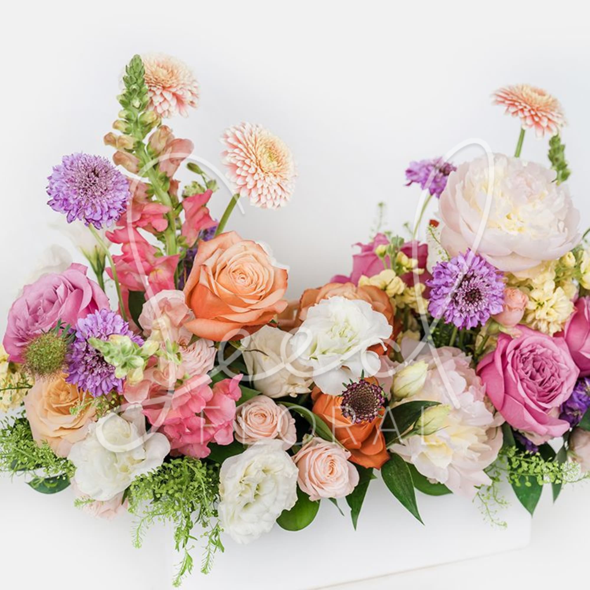 Mixed bouquet of roses, peonies, and purple blooms in soft pink and peach tones