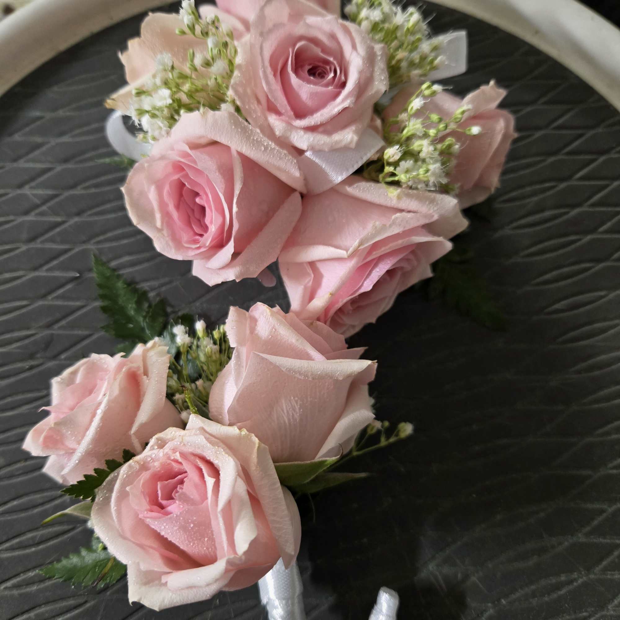 Pink rose corsage with white ribbon and small white filler flowers