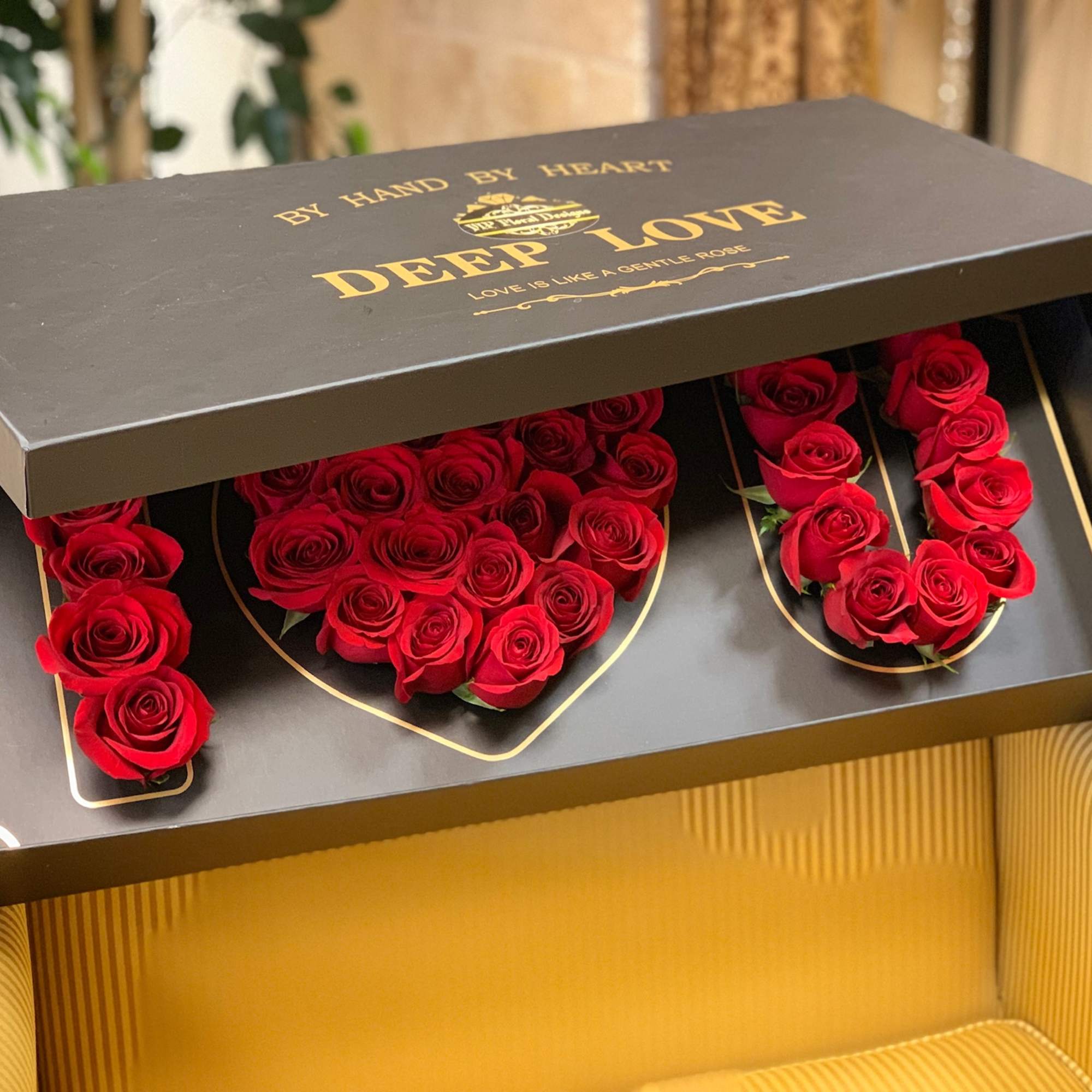 Red roses arranged in a black gift box with gold lettering