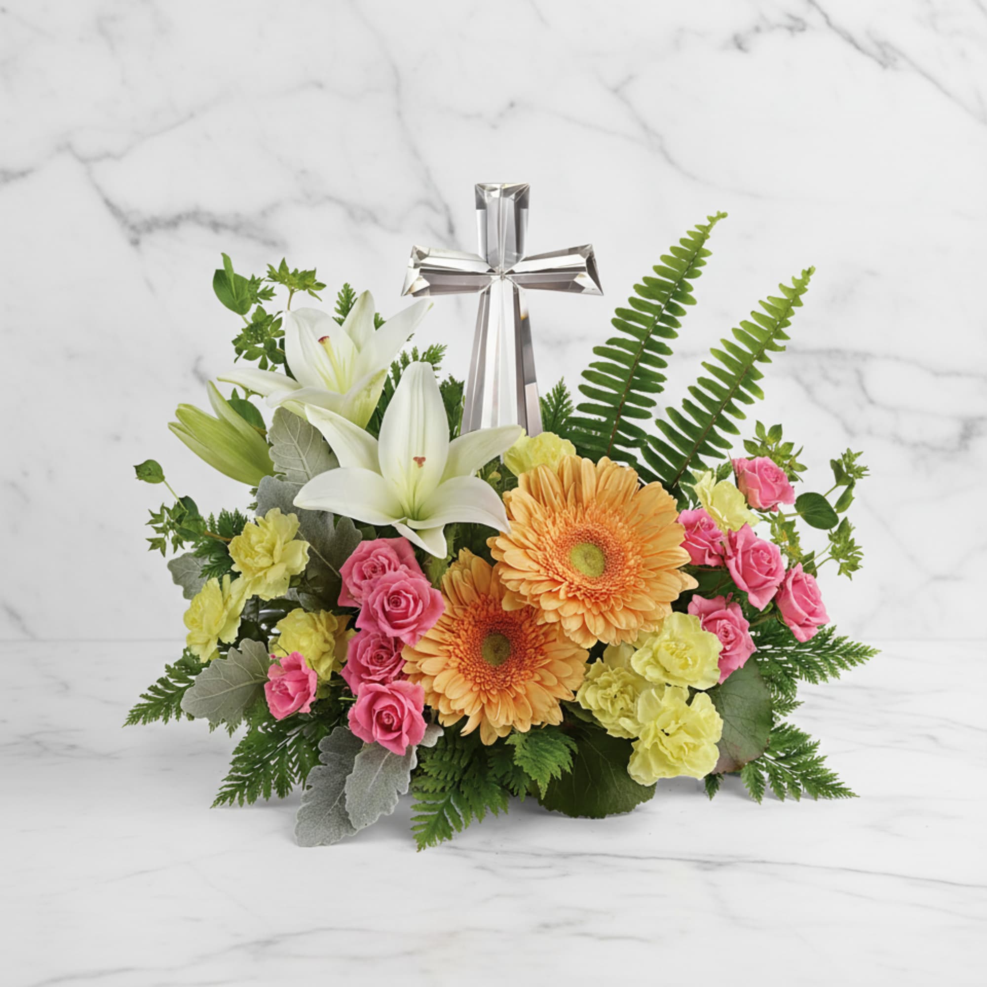 Floral arrangement with white lilies, pink roses, orange gerberas, and a silver cross