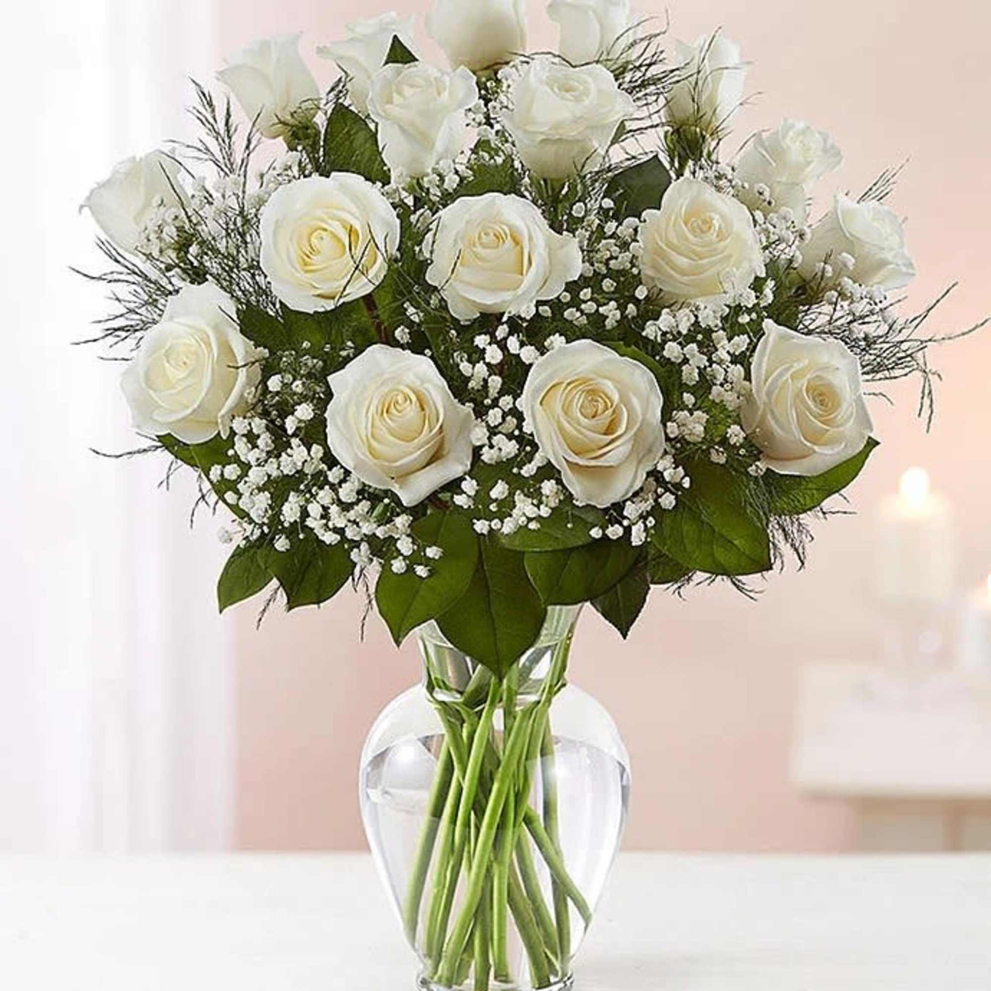White roses arranged in a clear glass vase with baby's breath
