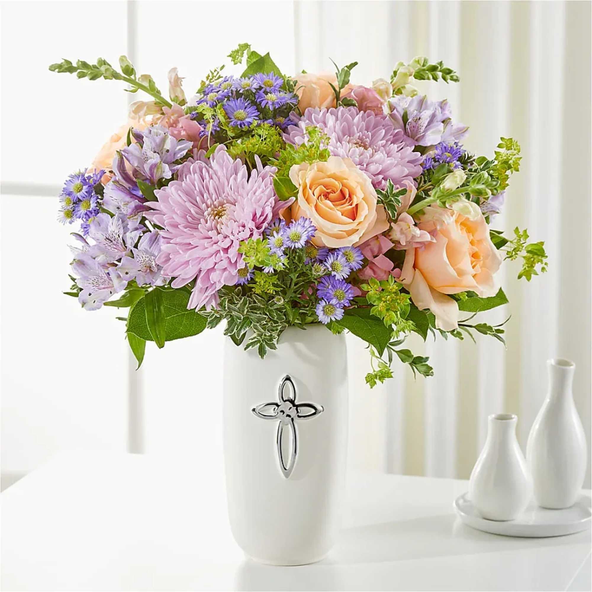 Pastel bouquet of roses, chrysanthemums, and purple daisies in a white vase