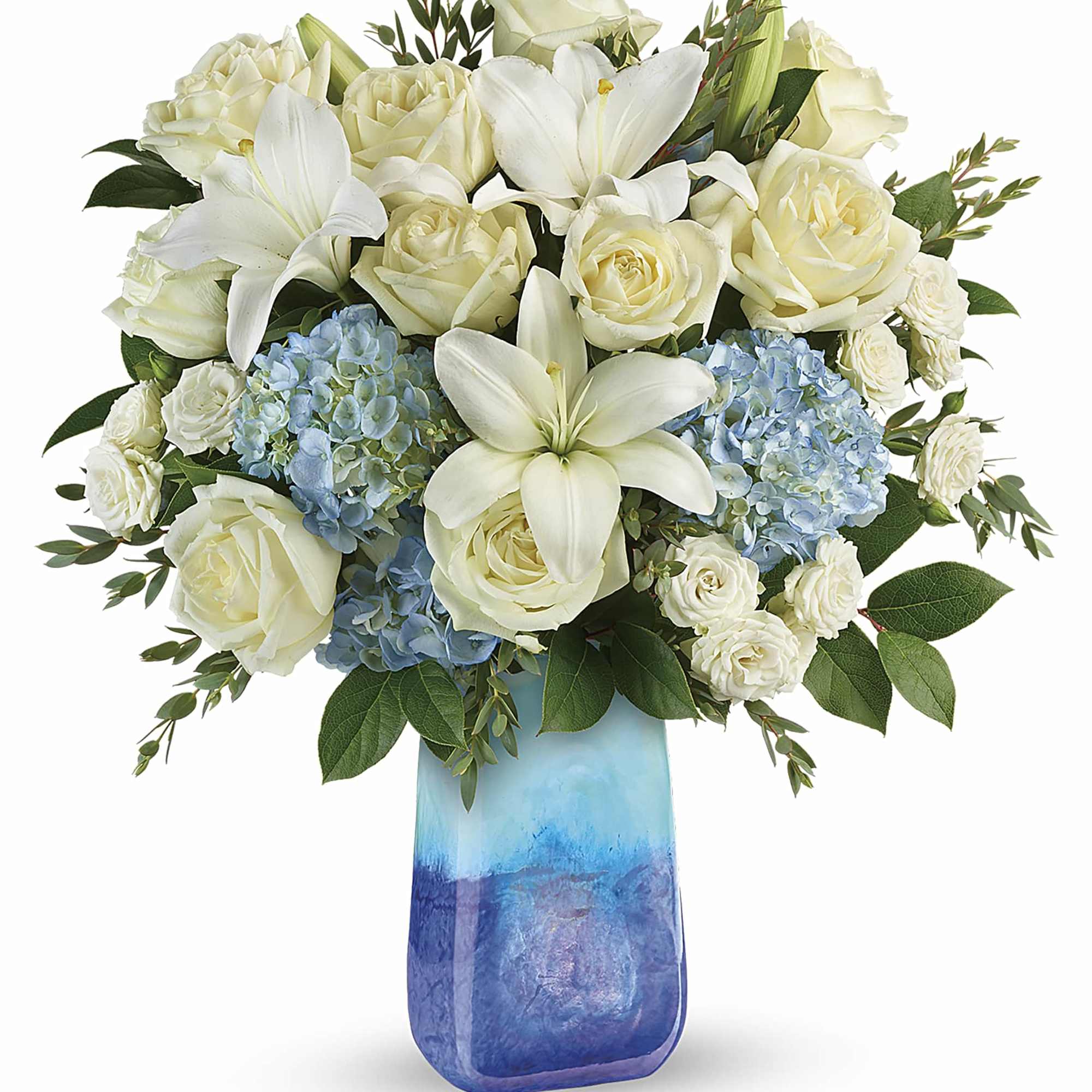 White roses and lilies with blue hydrangeas in a blue glass vase