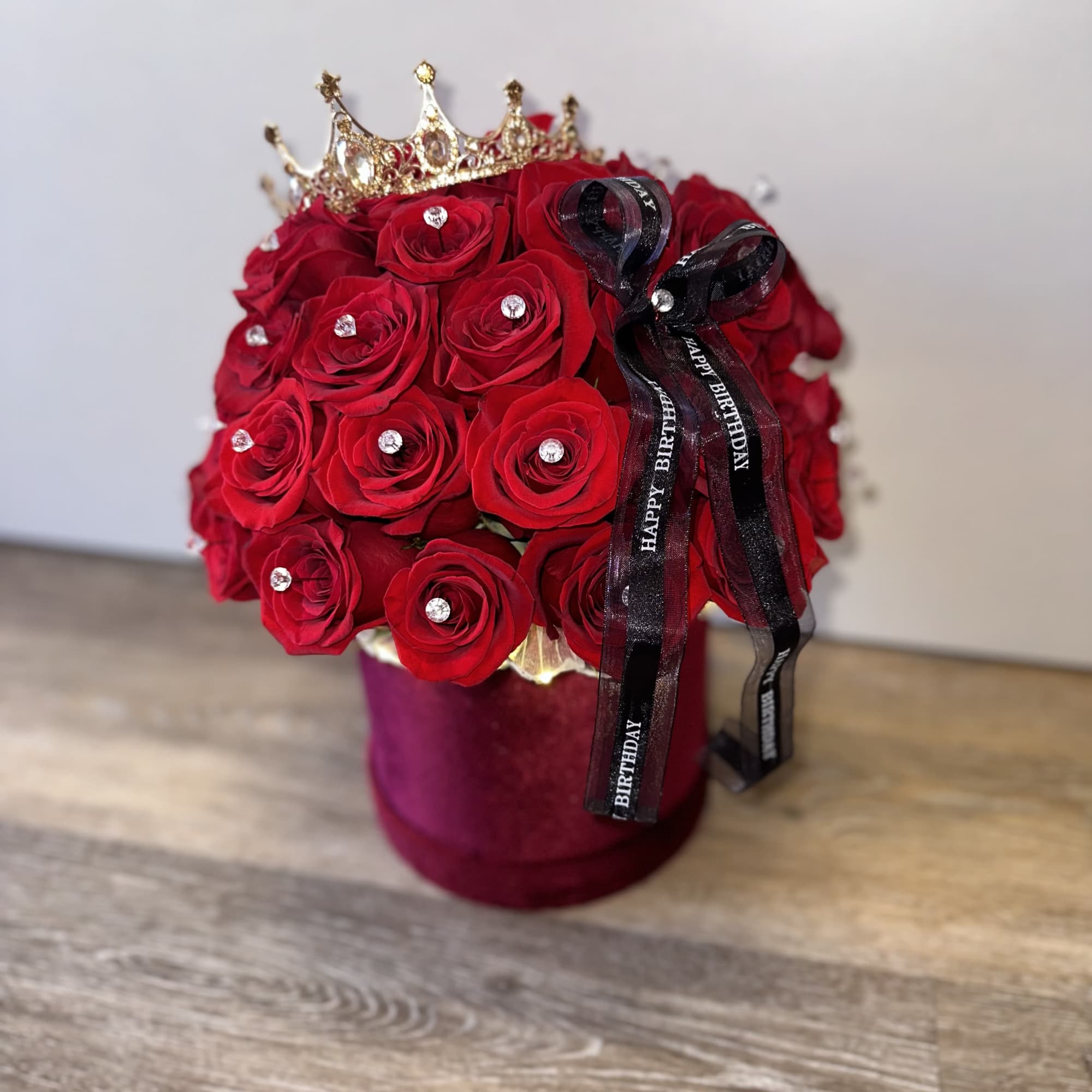 Red rose arrangement in a velvet box with a crown and birthday ribbon