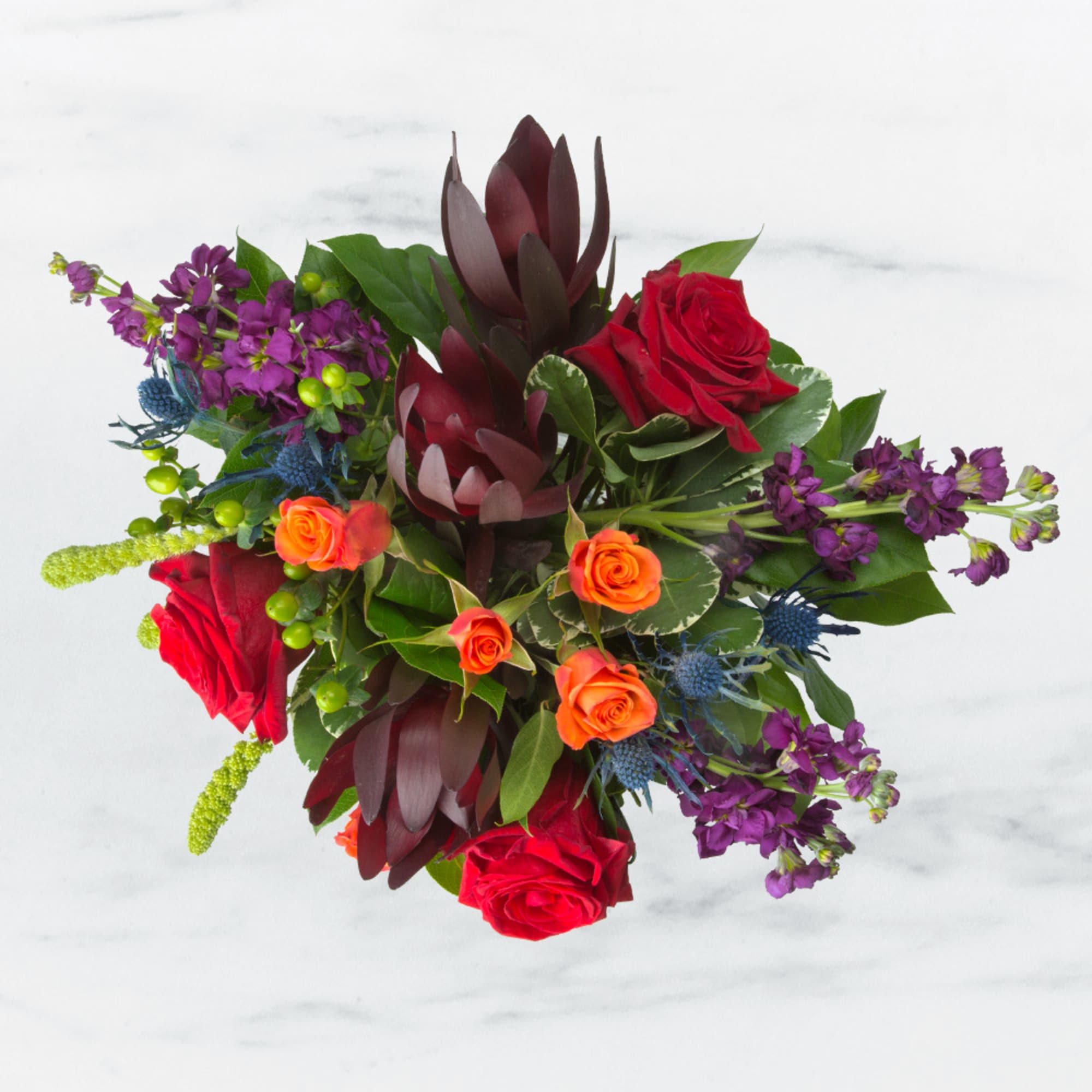 Bouquet of red and orange roses with purple flowers and dark burgundy foliage