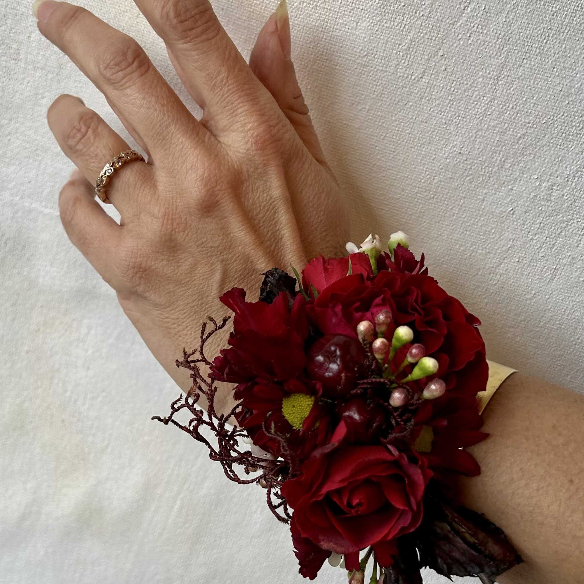 Red floral wrist corsage with roses on a person's wrist