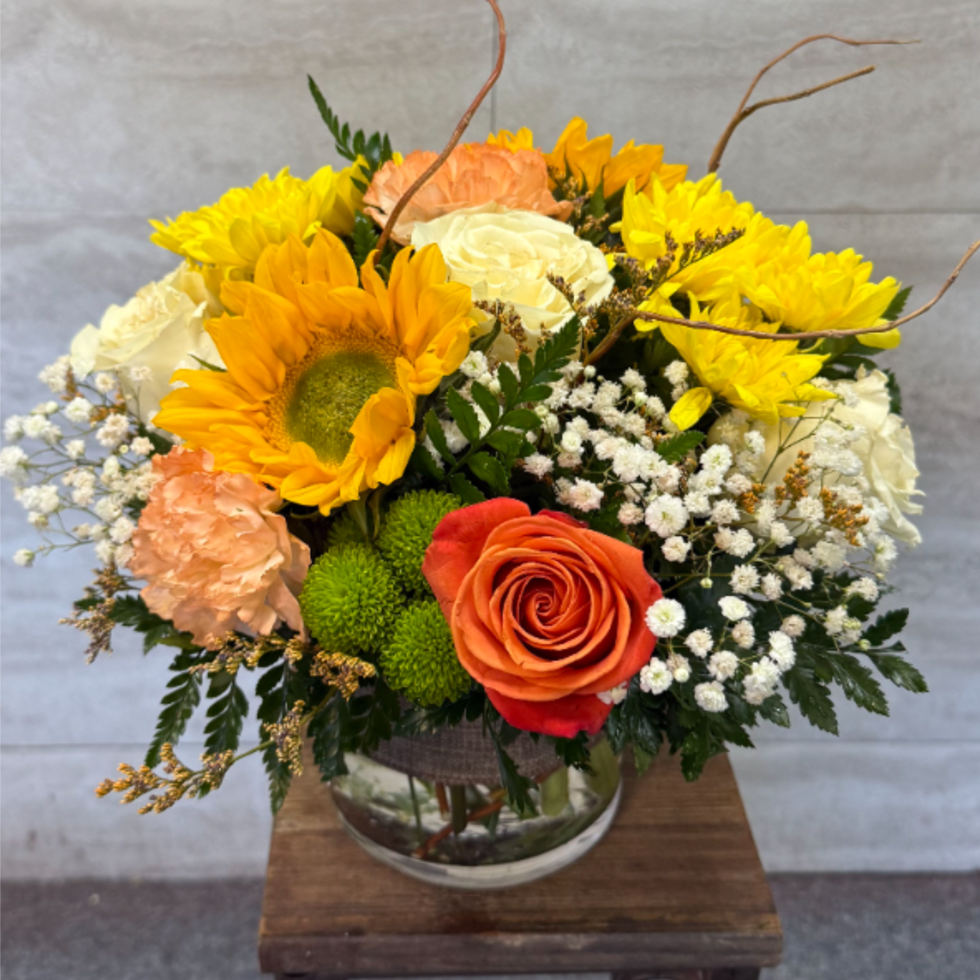 (ALL-ROUNDED) A cheerful mix of sunflowers, creamy roses, peach carnations, and a