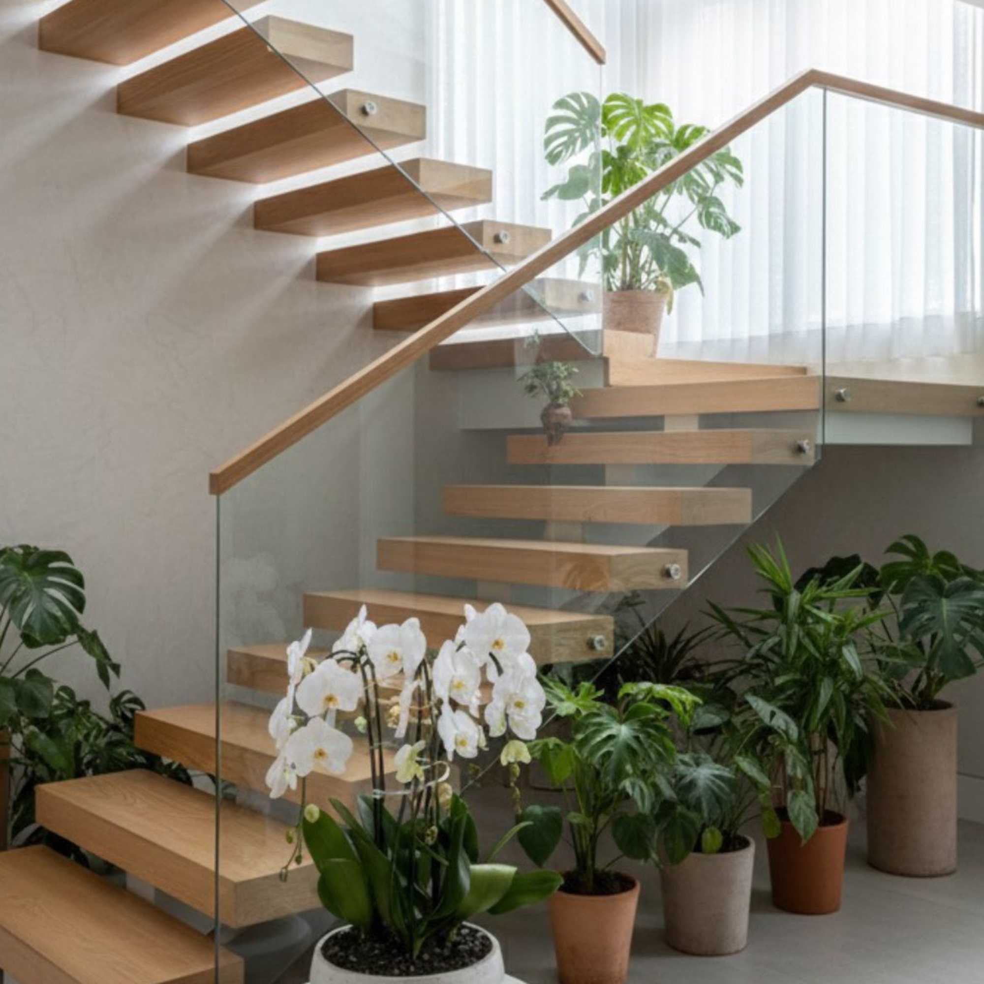 White orchid plant in a bowl on a round pedestal beside indoor stairs