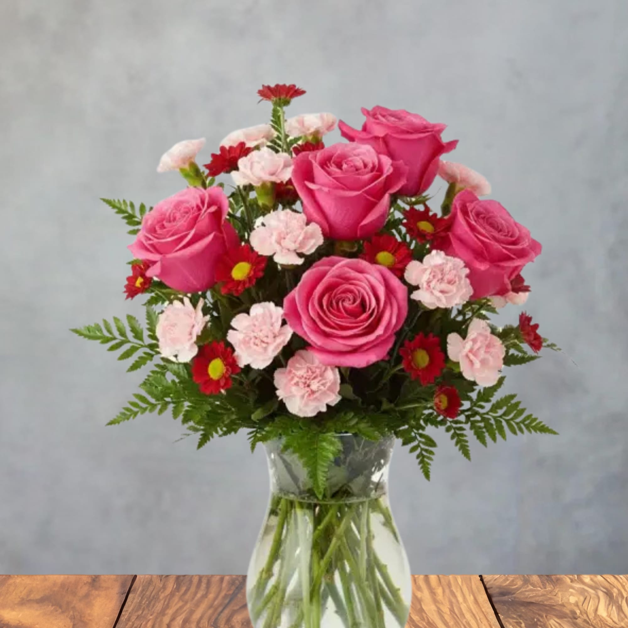 Bright pink roses take center stage in this cheerful, romantic flower arrangement-perfect