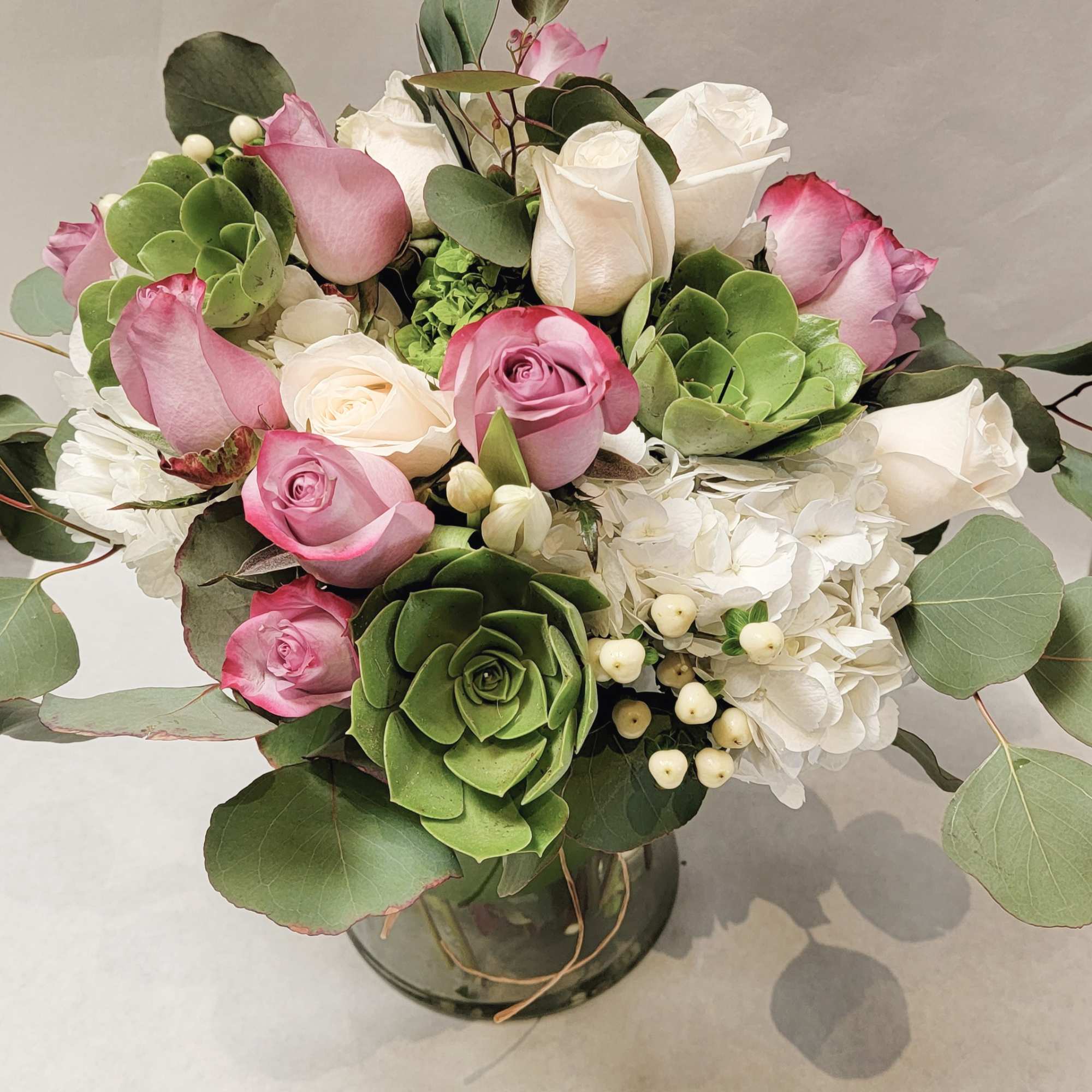 Pink and white roses arranged with hydrangea in a glass vase