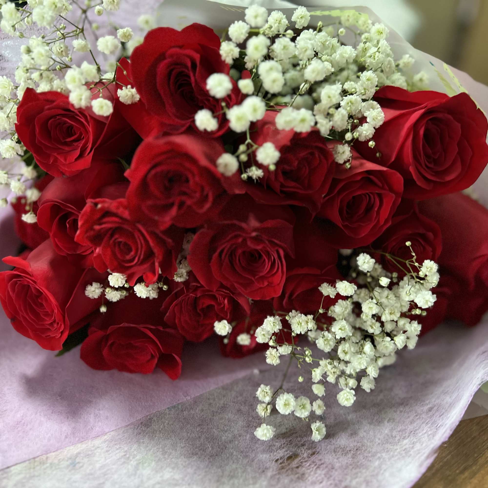 Bouquet of red roses with white baby's breath in pale wrapping