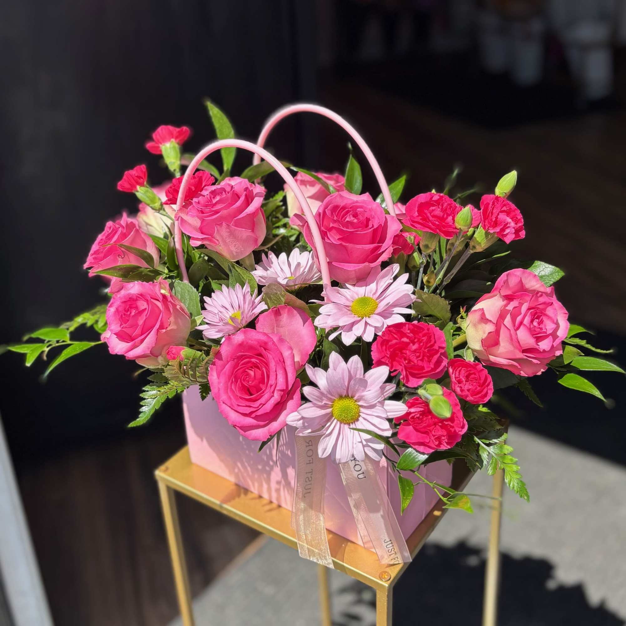 Pink roses and daisies arranged in a pink gift basket