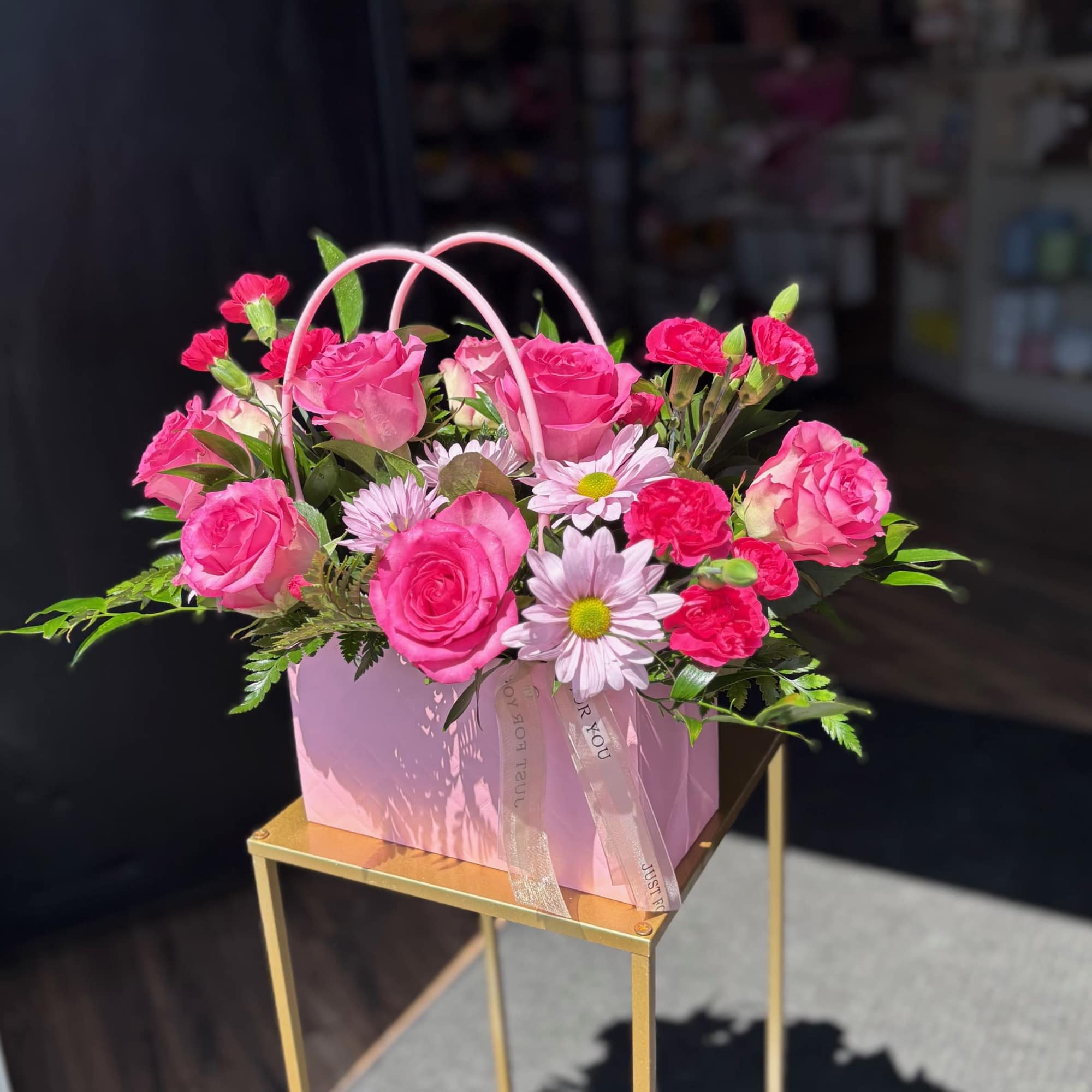 Pink roses and carnations in a pink gift box with ribbon handles