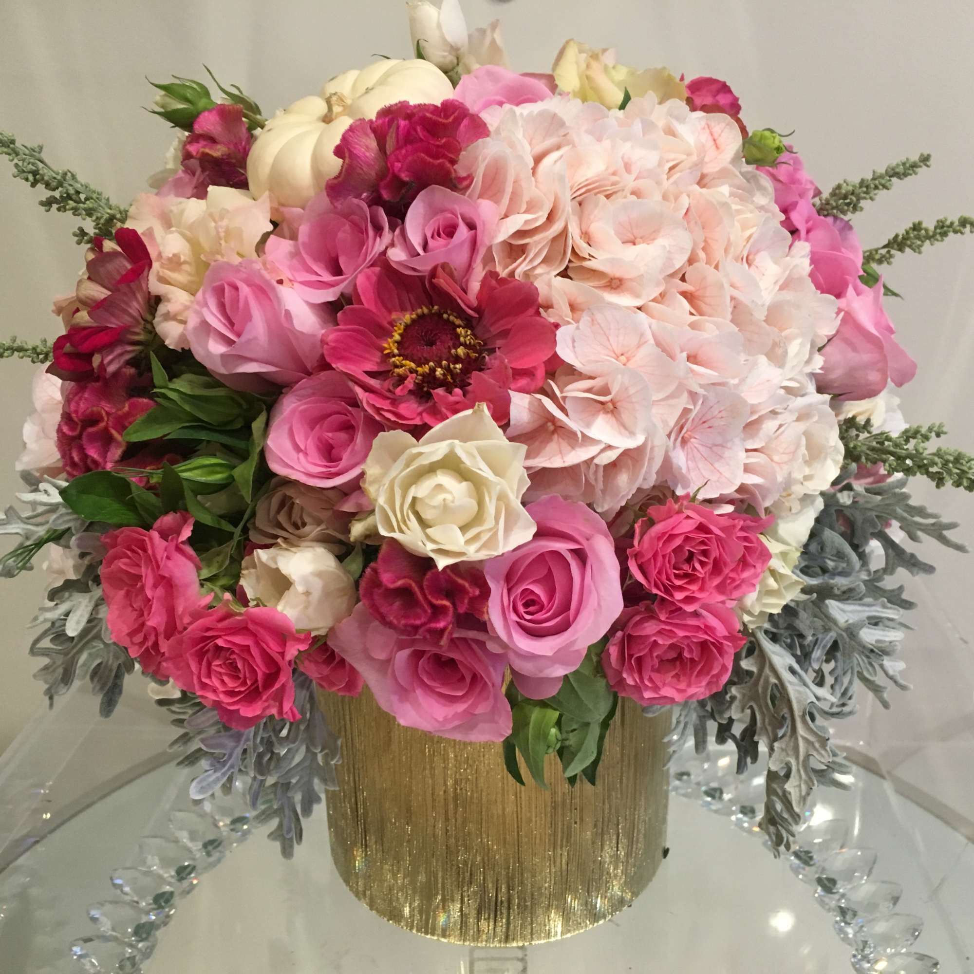 Pink and white flower arrangement in a gold vase