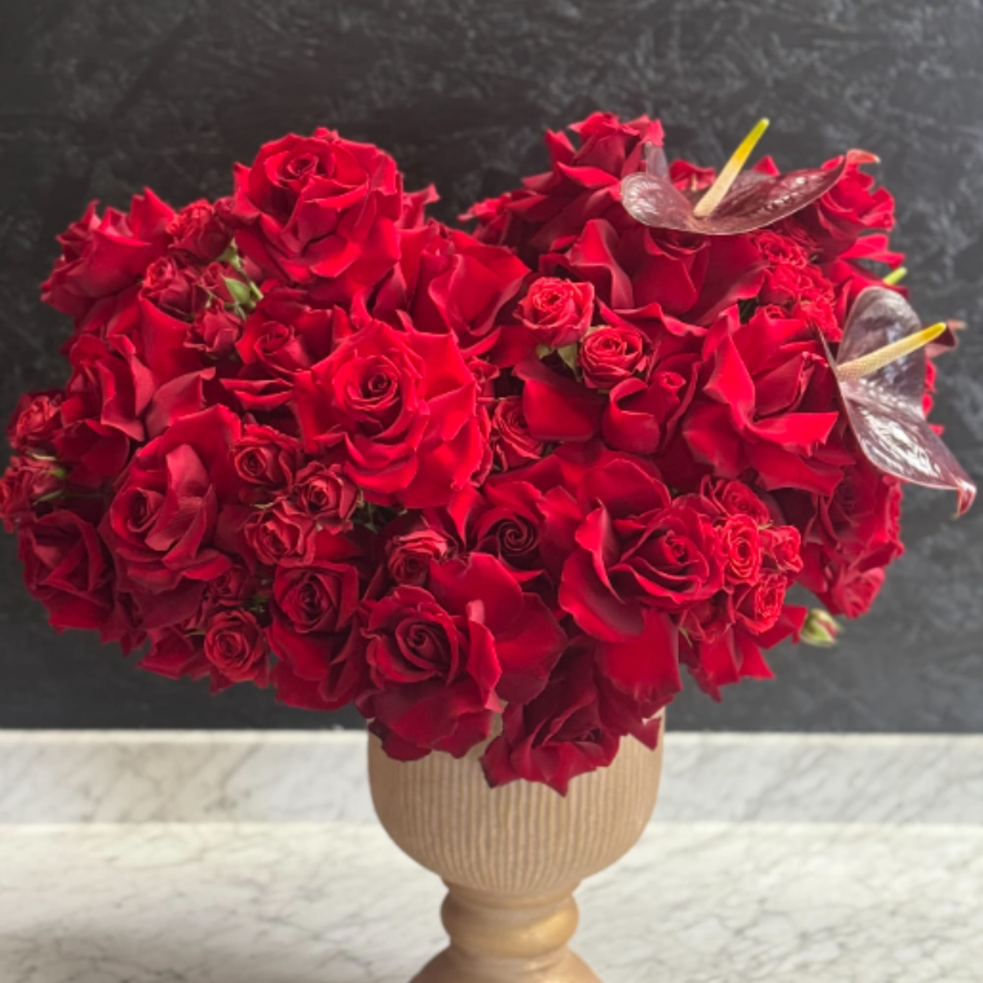 A lush , statement arrangement overflowing with velvety red roses accented with