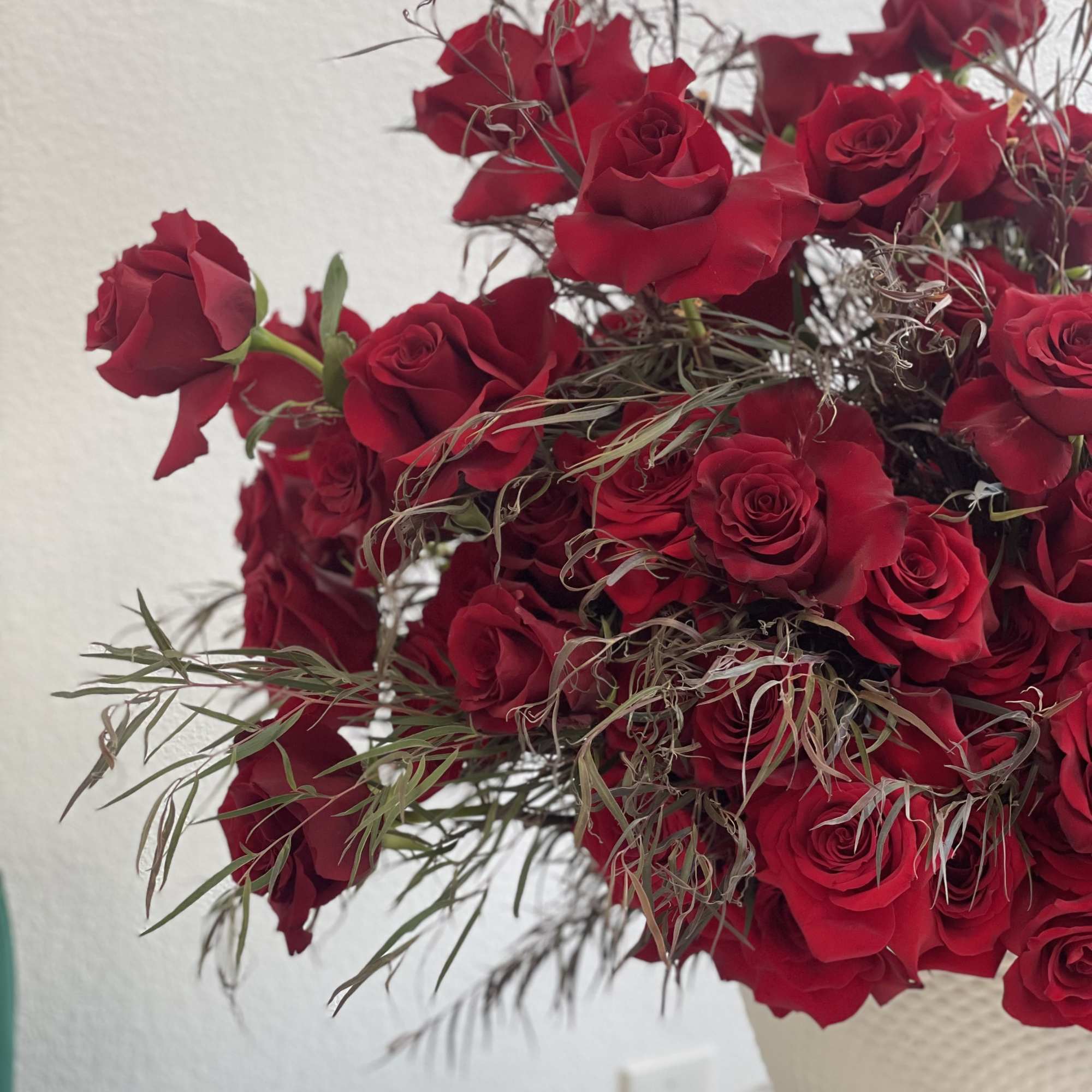 Bouquet of red roses with wispy filler in a white vase