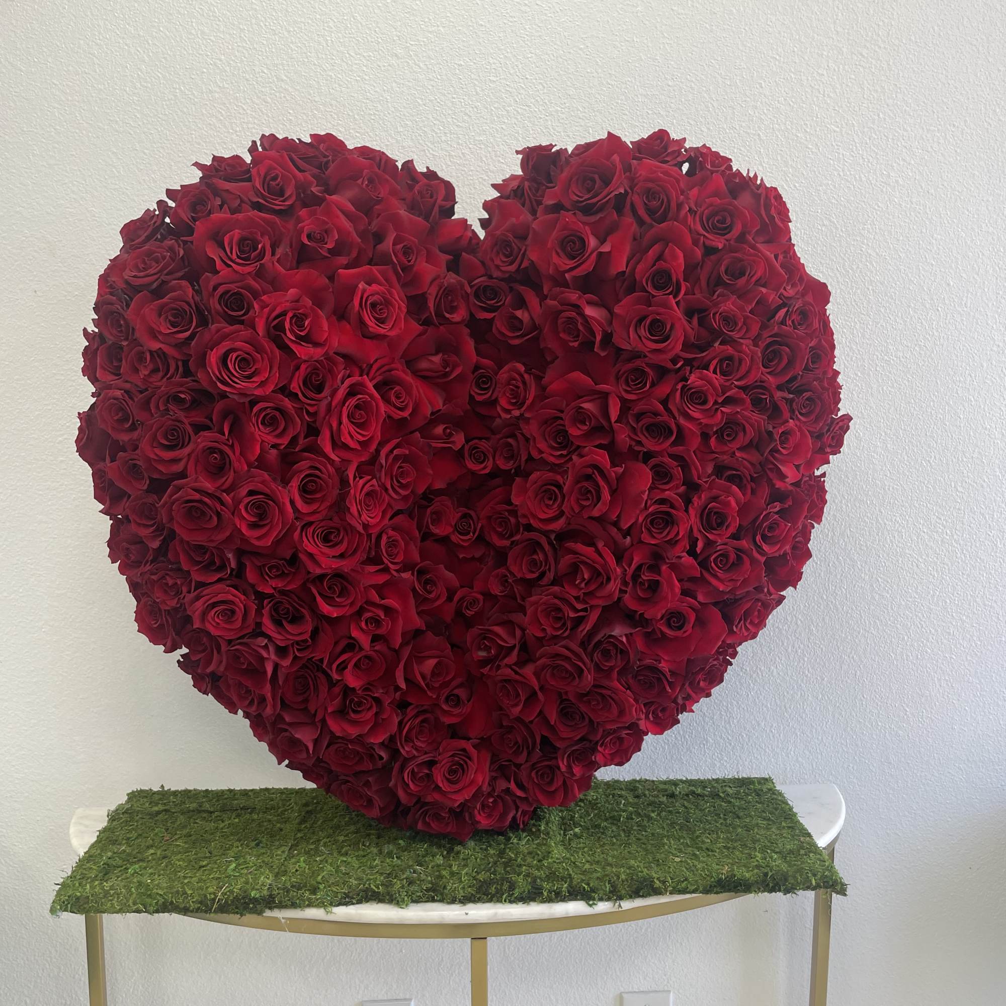 Heart-shaped arrangement of red roses on a table
