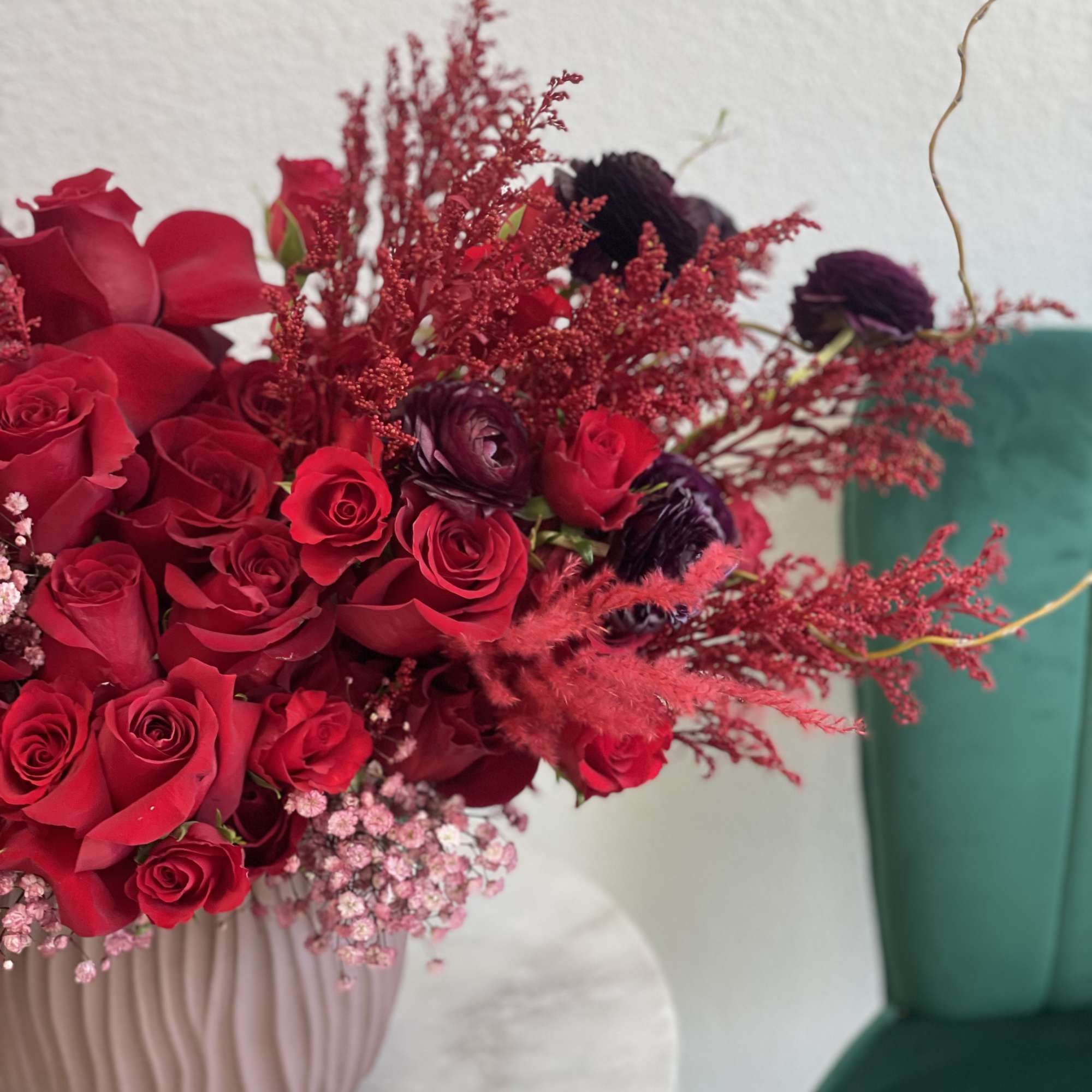 Red rose arrangement in a pink ribbed vase