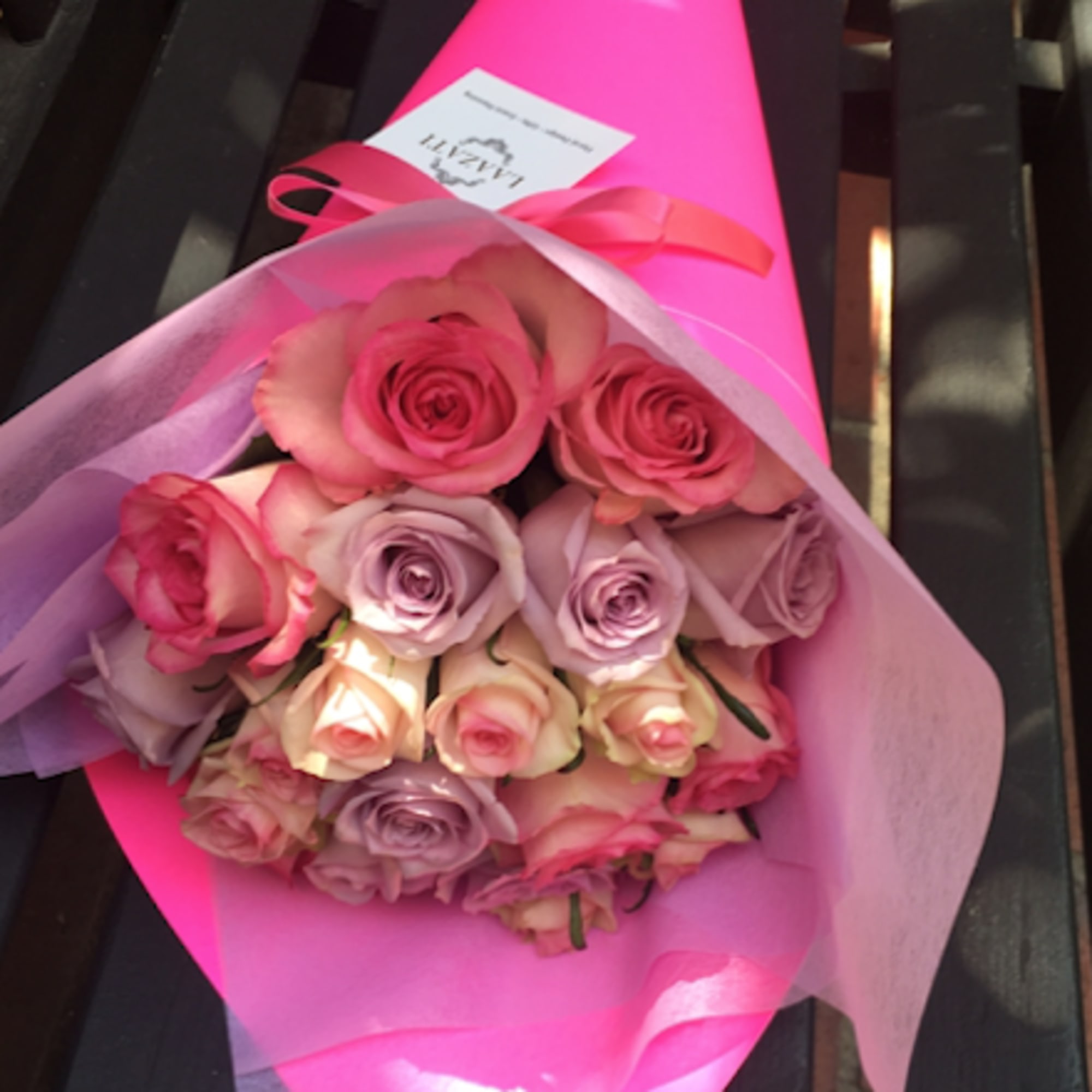 Bouquet of pink and lavender roses wrapped in bright pink paper