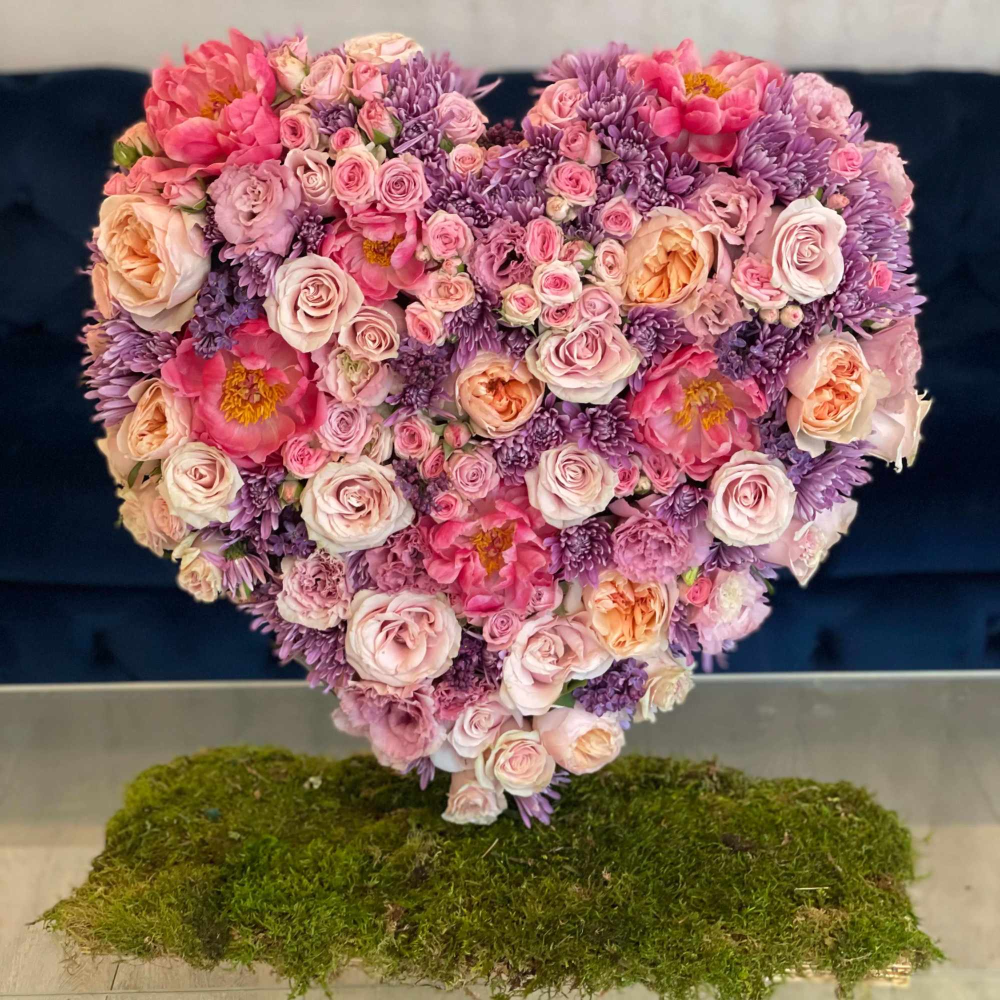 Heart-shaped bouquet of pink and purple flowers on a moss base