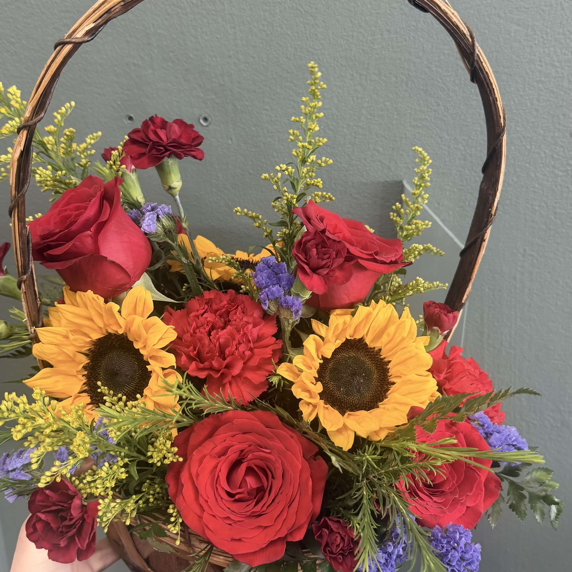 A bright, handpicked basket arrangement that pairs golden sunflowers with classic red
