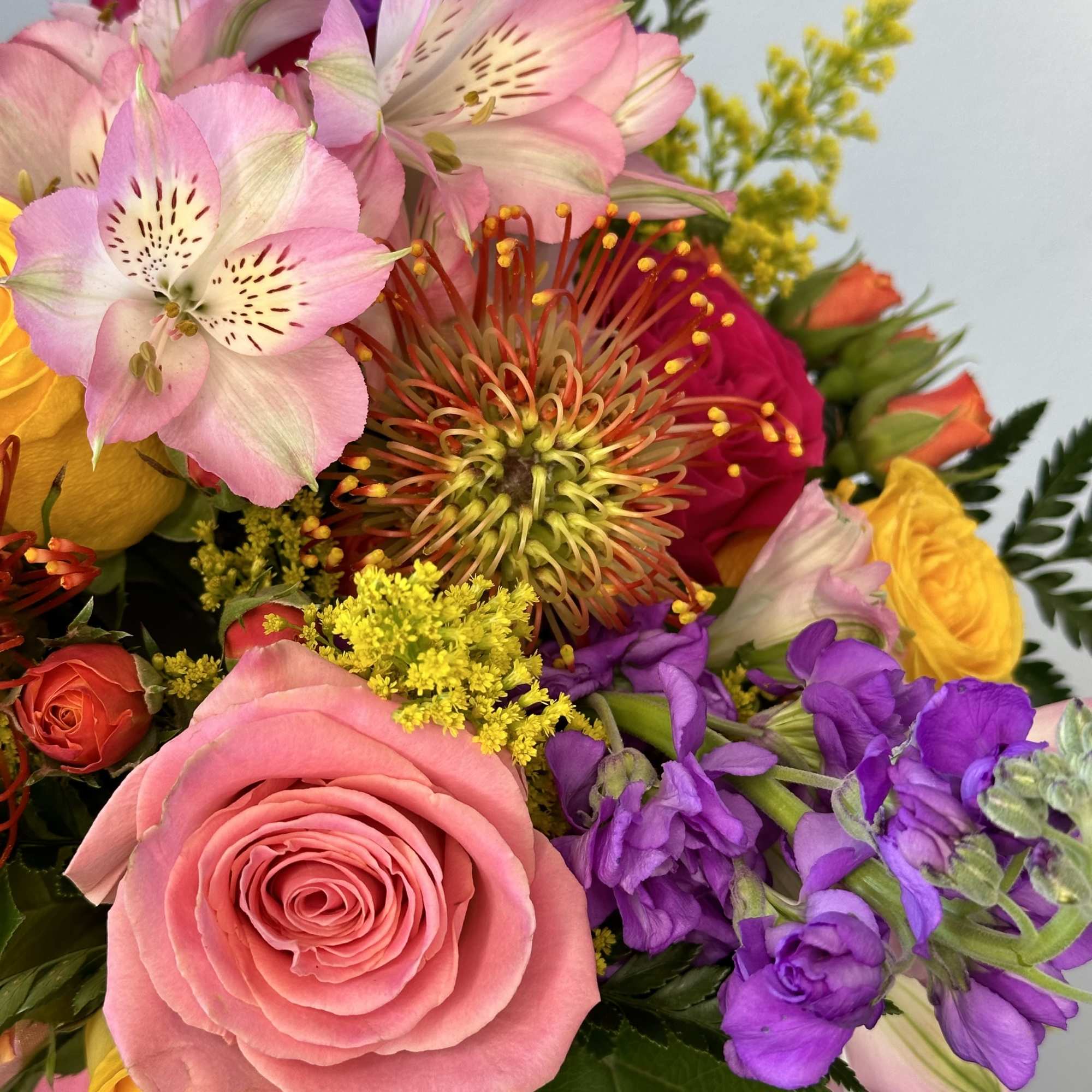 Colorful bouquet with pink roses, purple blooms, and yellow flowers