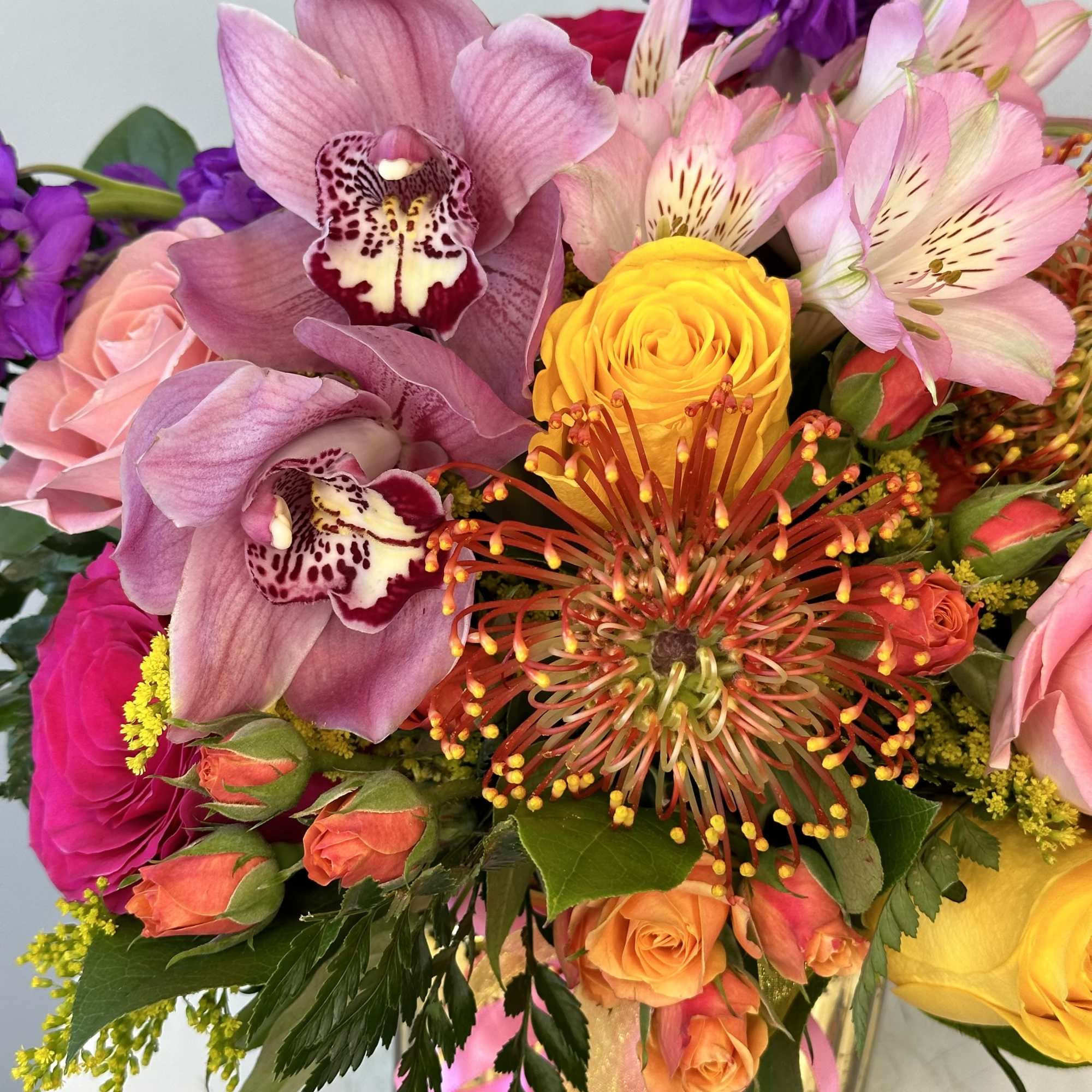 Mixed bouquet with pink orchids, roses, and yellow blooms