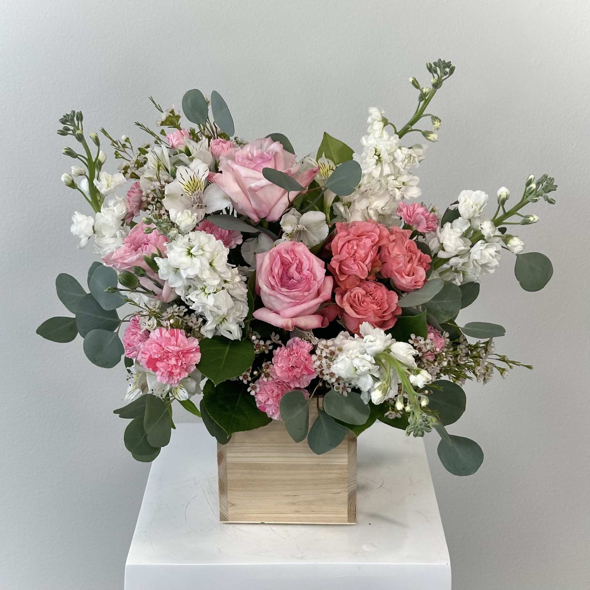 Pink and white floral arrangement in a wooden box