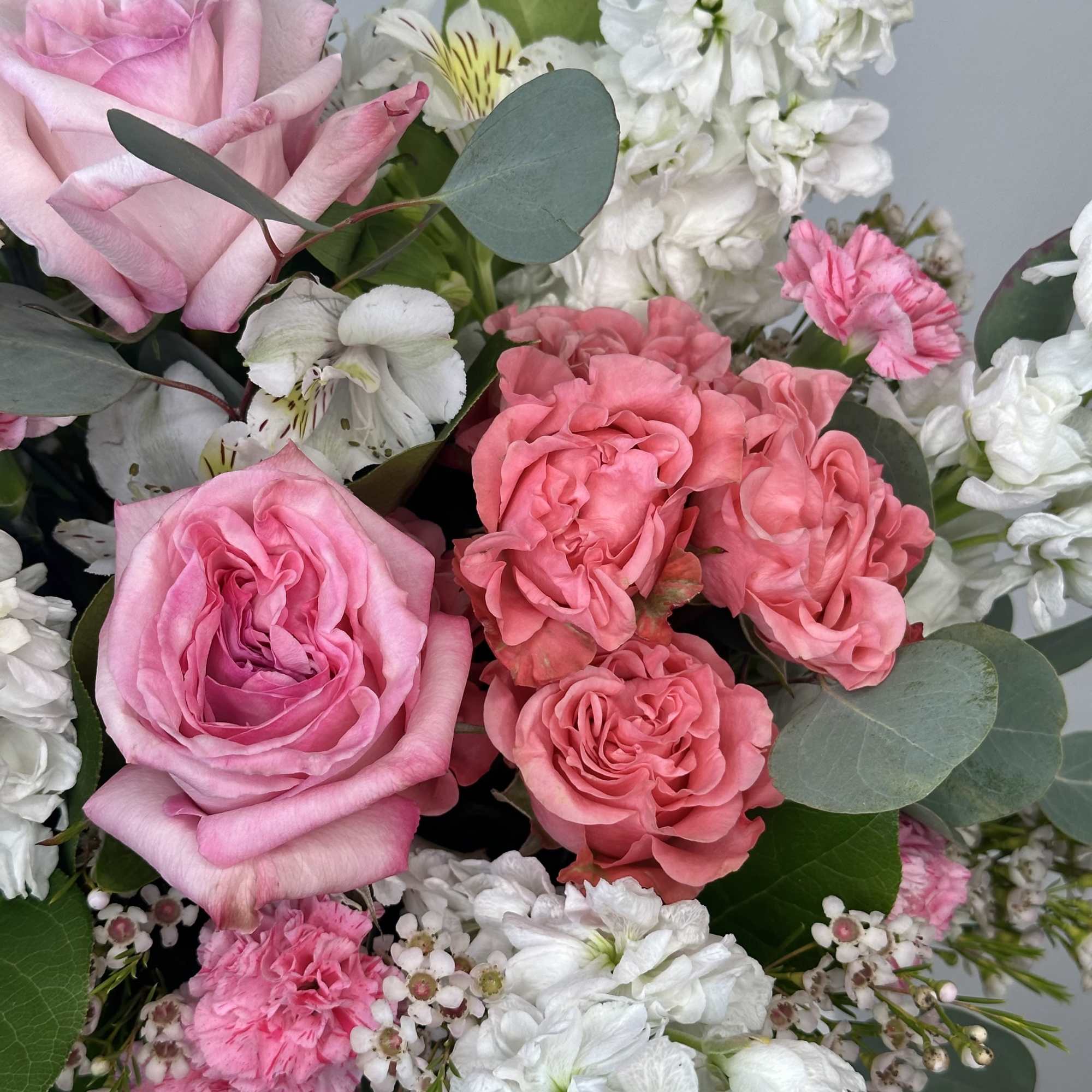 Pink roses with white blooms and greenery in a bouquet