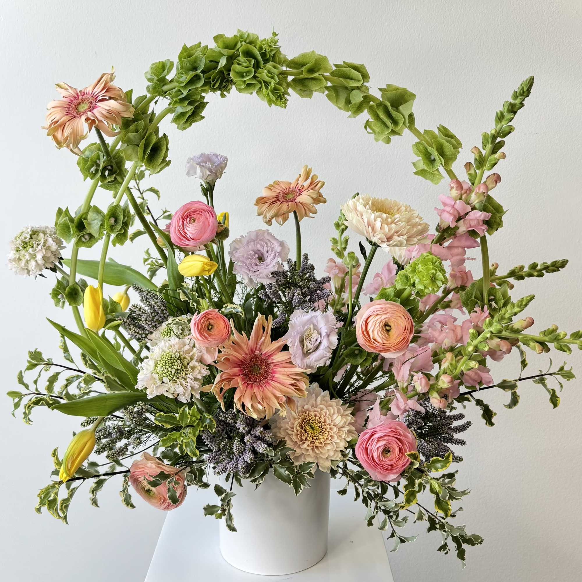 Mixed pastel bouquet in a white vase with pink, peach, and yellow blooms