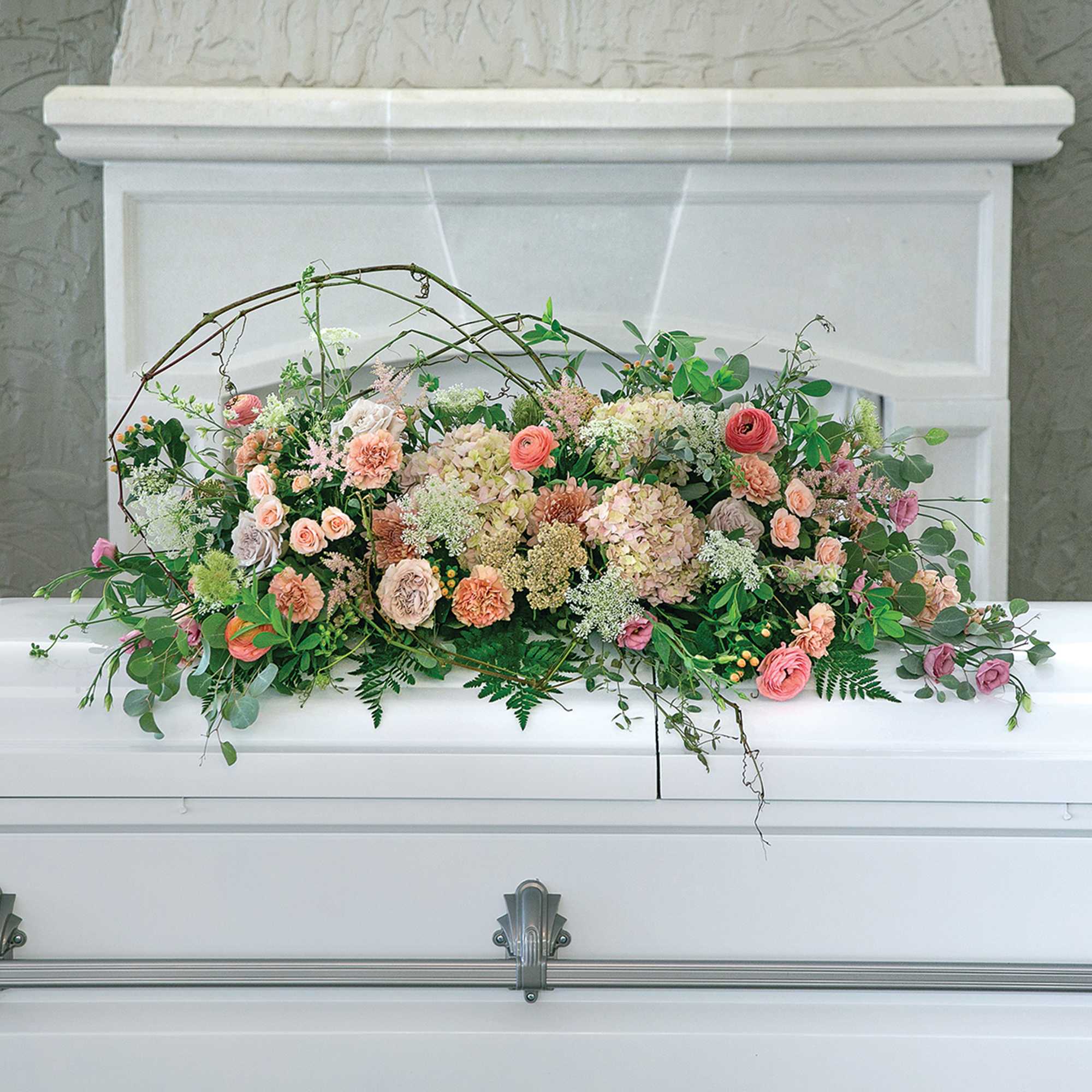 Pastel floral arrangement on a white casket