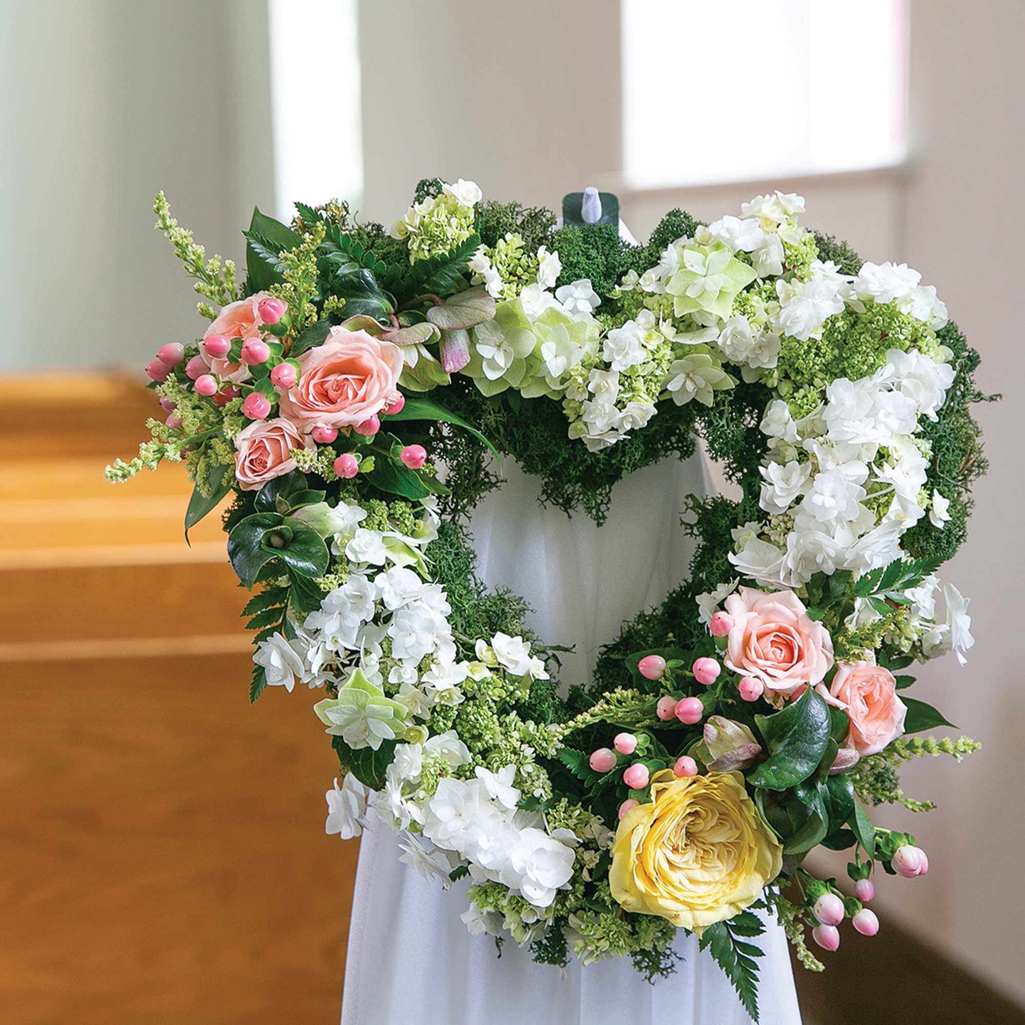 Heart-shaped floral wreath with pink, white, and yellow flowers