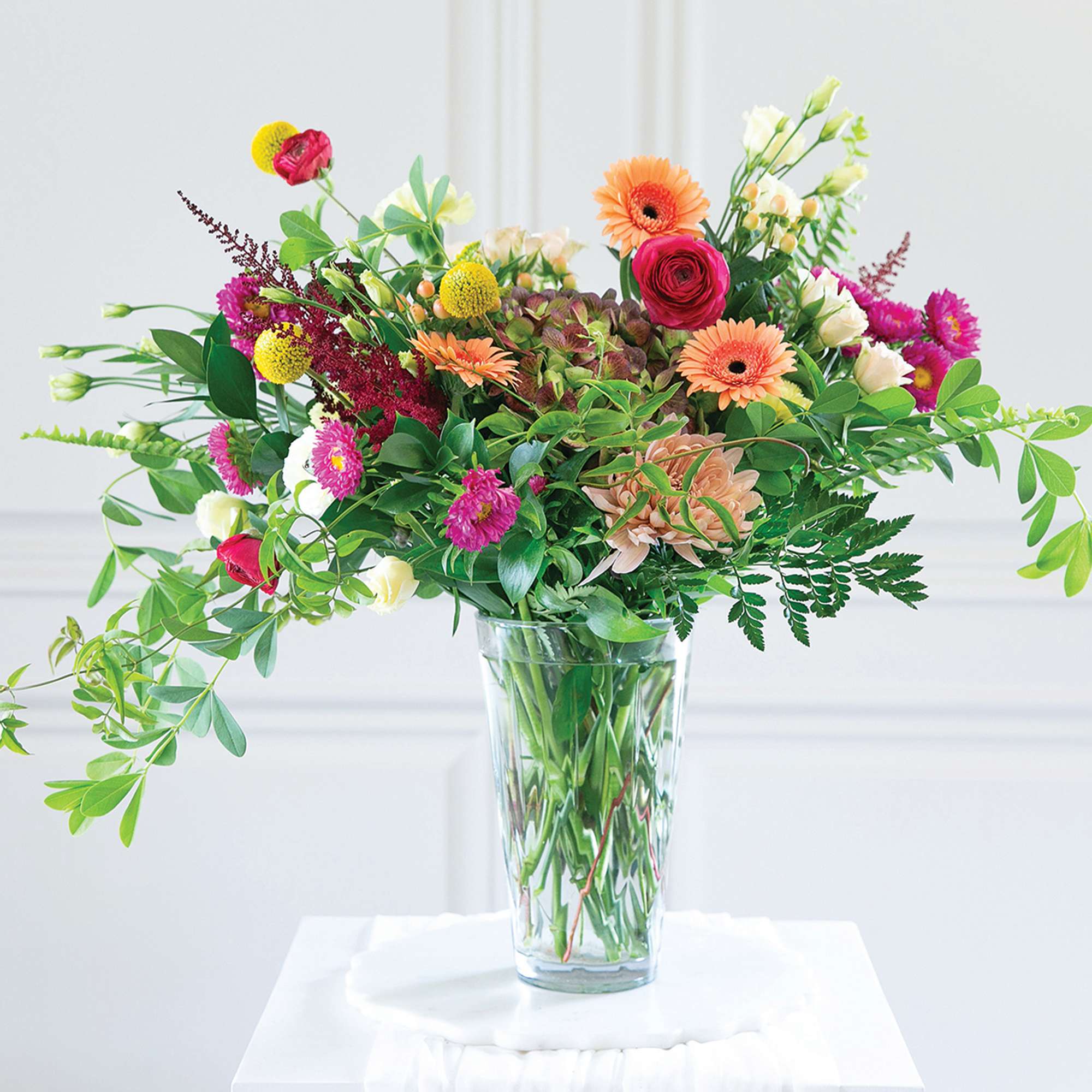 Mixed bouquet of bright flowers in a clear glass vase