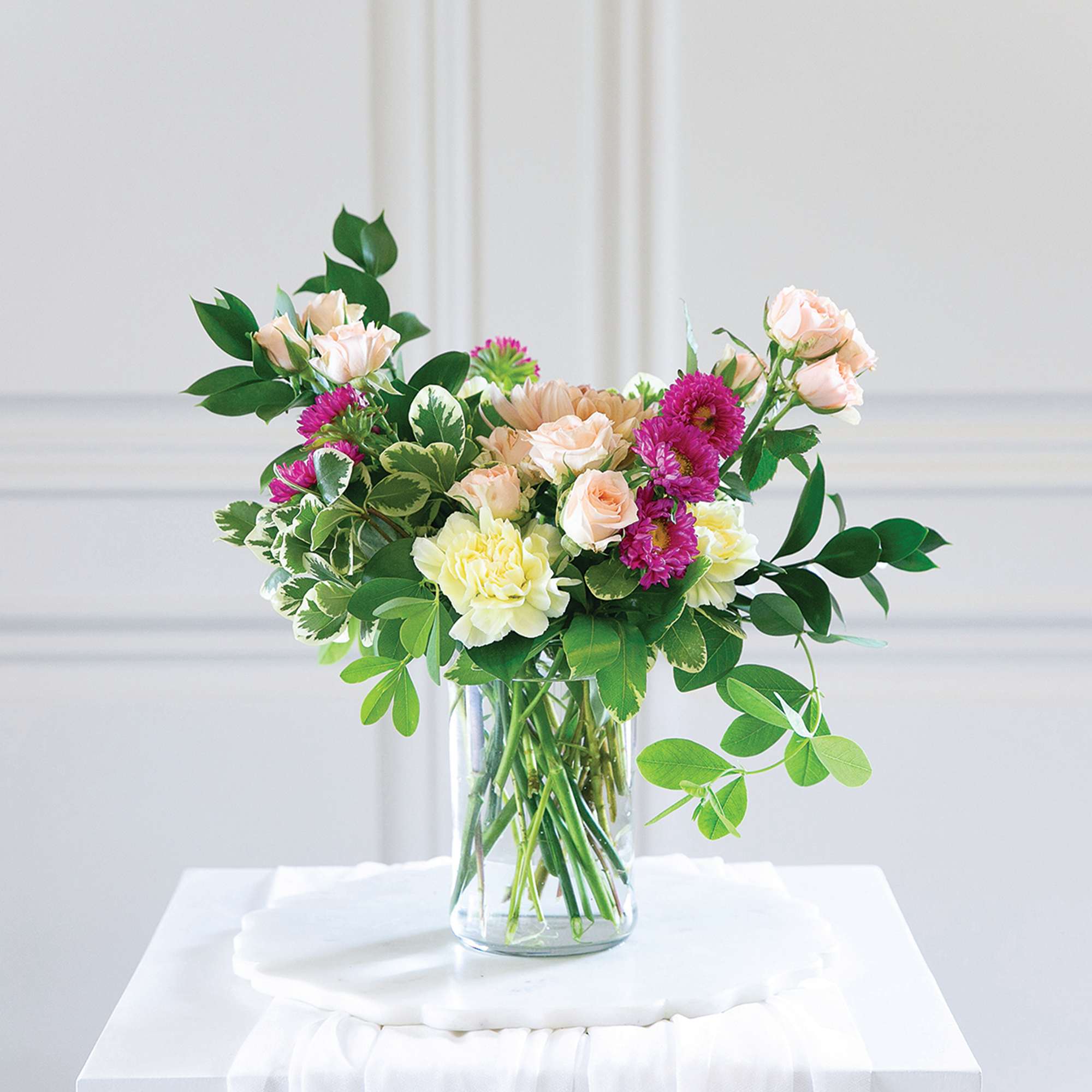 Bouquet of pale roses and pink daisies in a clear glass vase