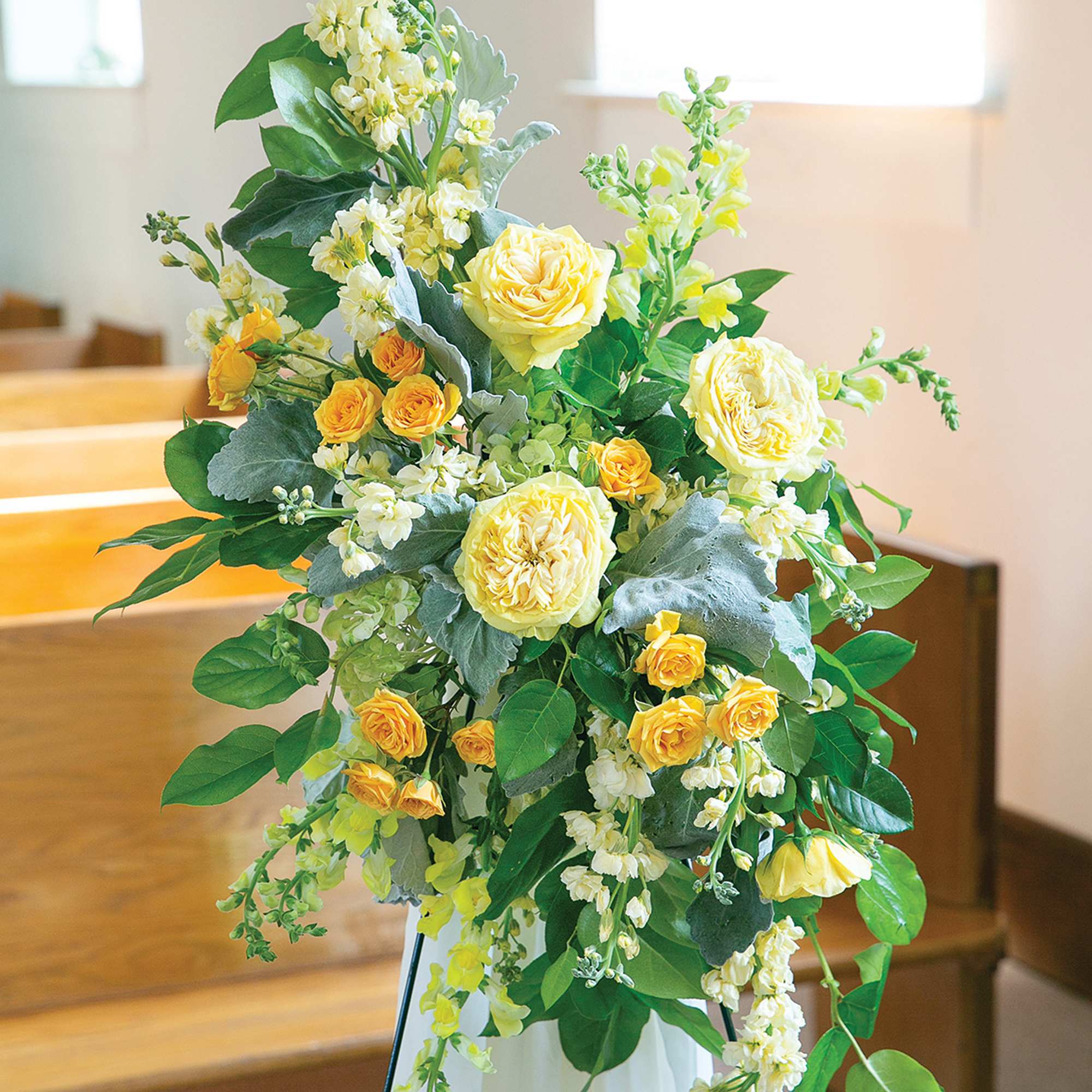 Tall yellow and white floral arrangement on a stand
