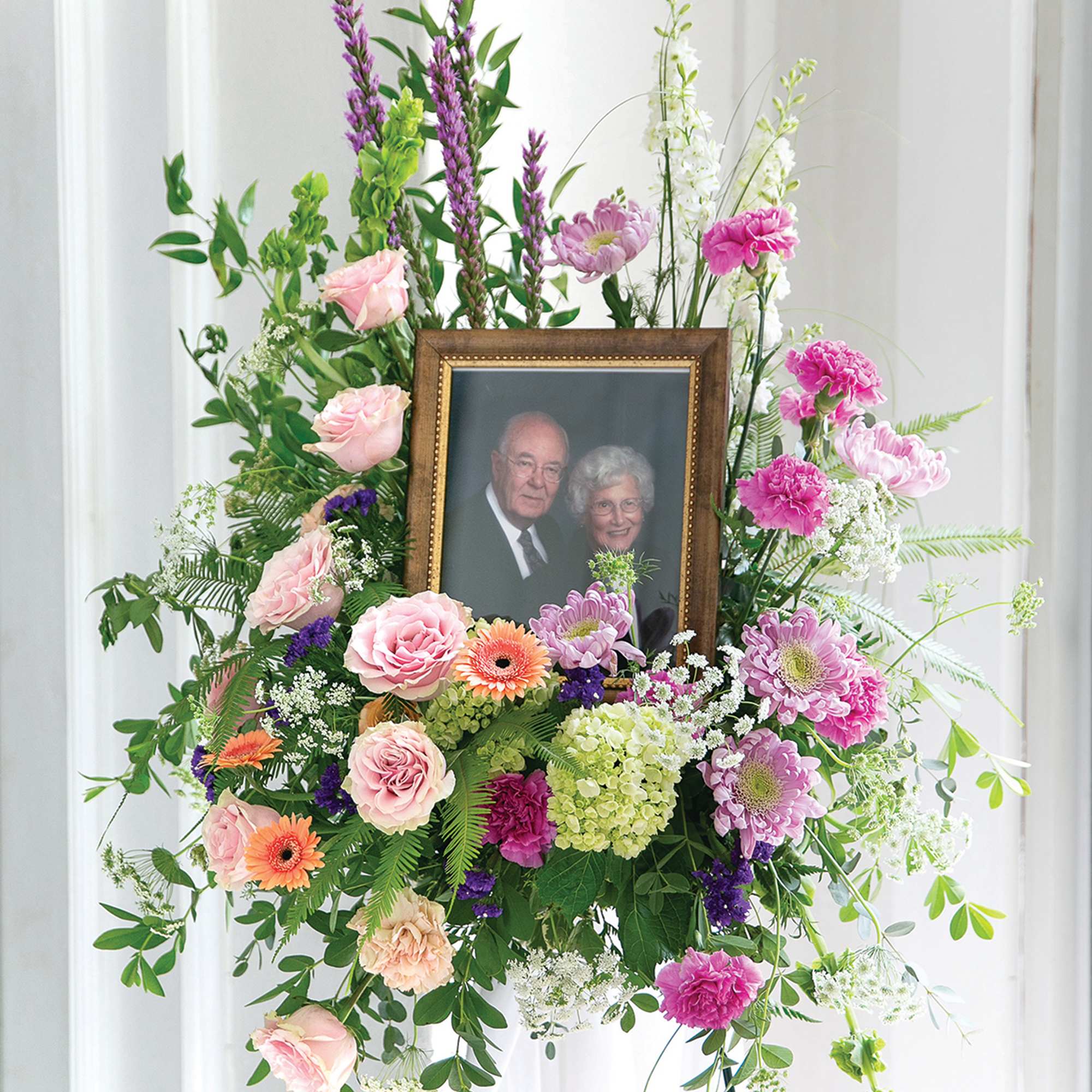 Standing floral tribute with a framed photo at center