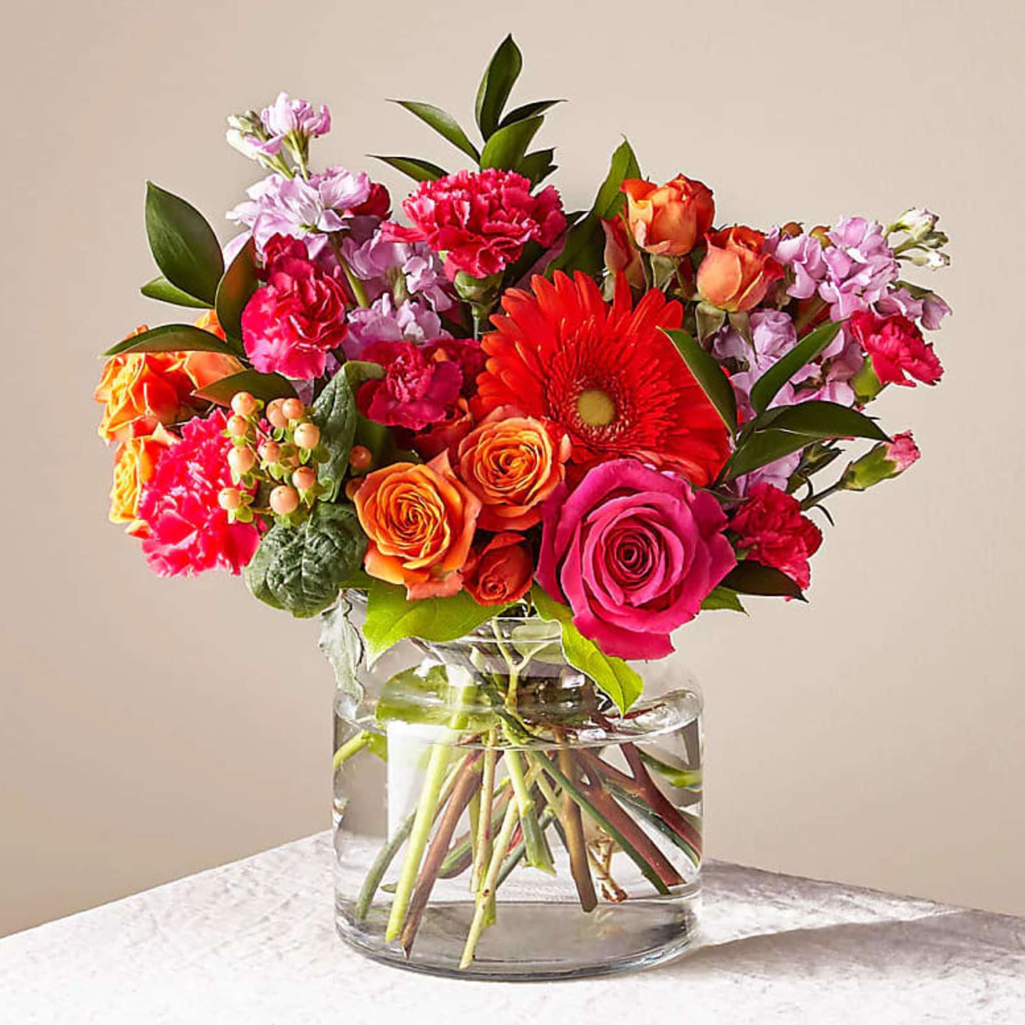 Mixed bouquet of roses, gerbera daisies, and carnations in a glass vase