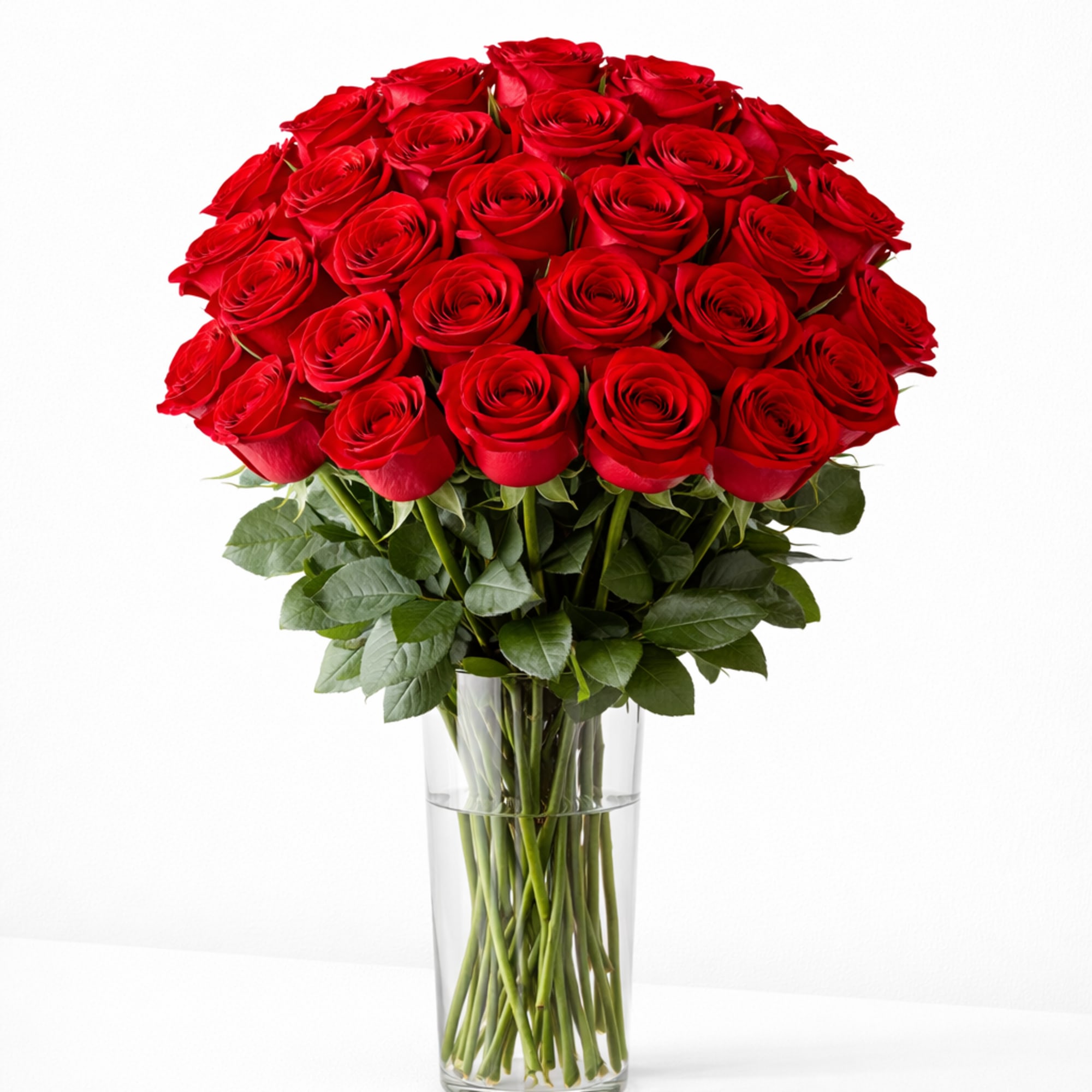 Tall clear glass vase filled with a large bouquet of red roses.