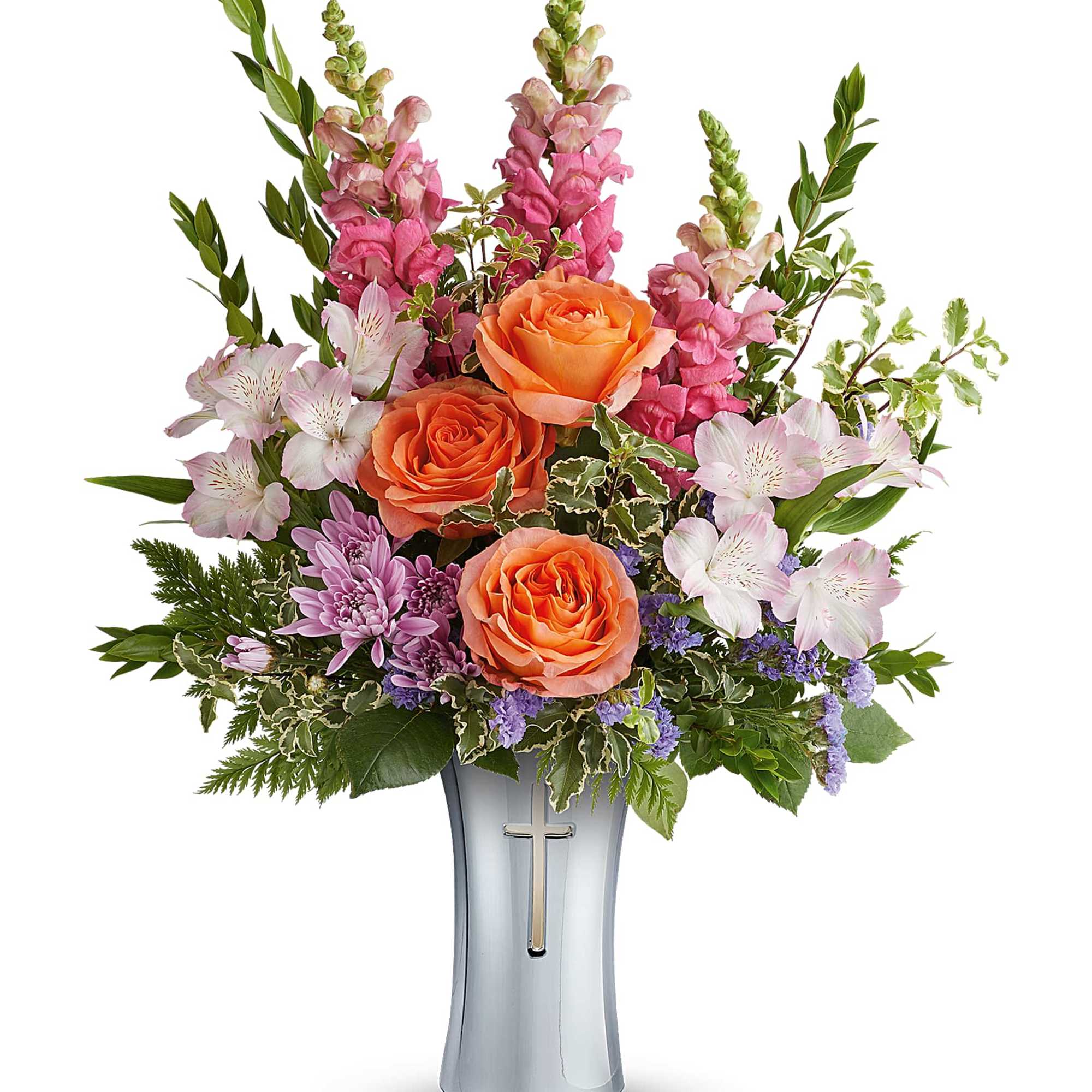 Orange roses and pink snapdragons in a silver vase with a cross