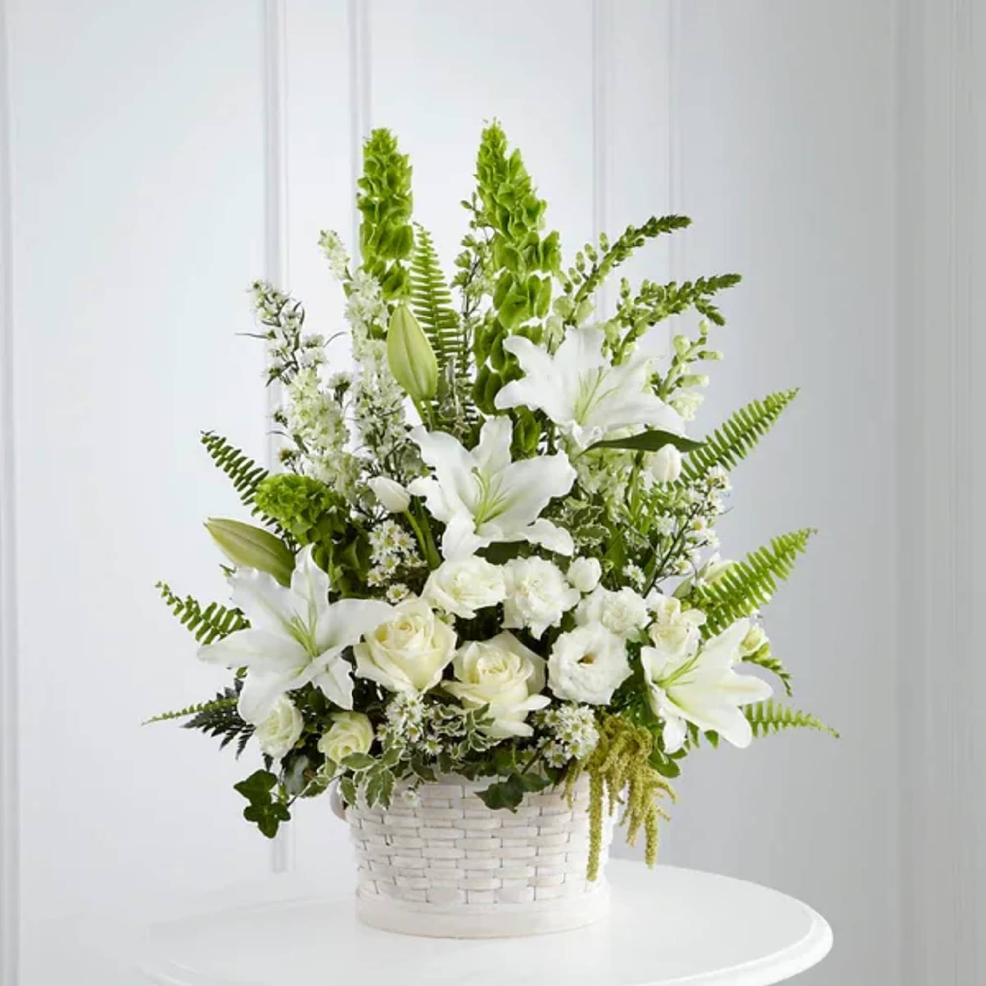 White lilies and roses arranged in a white basket