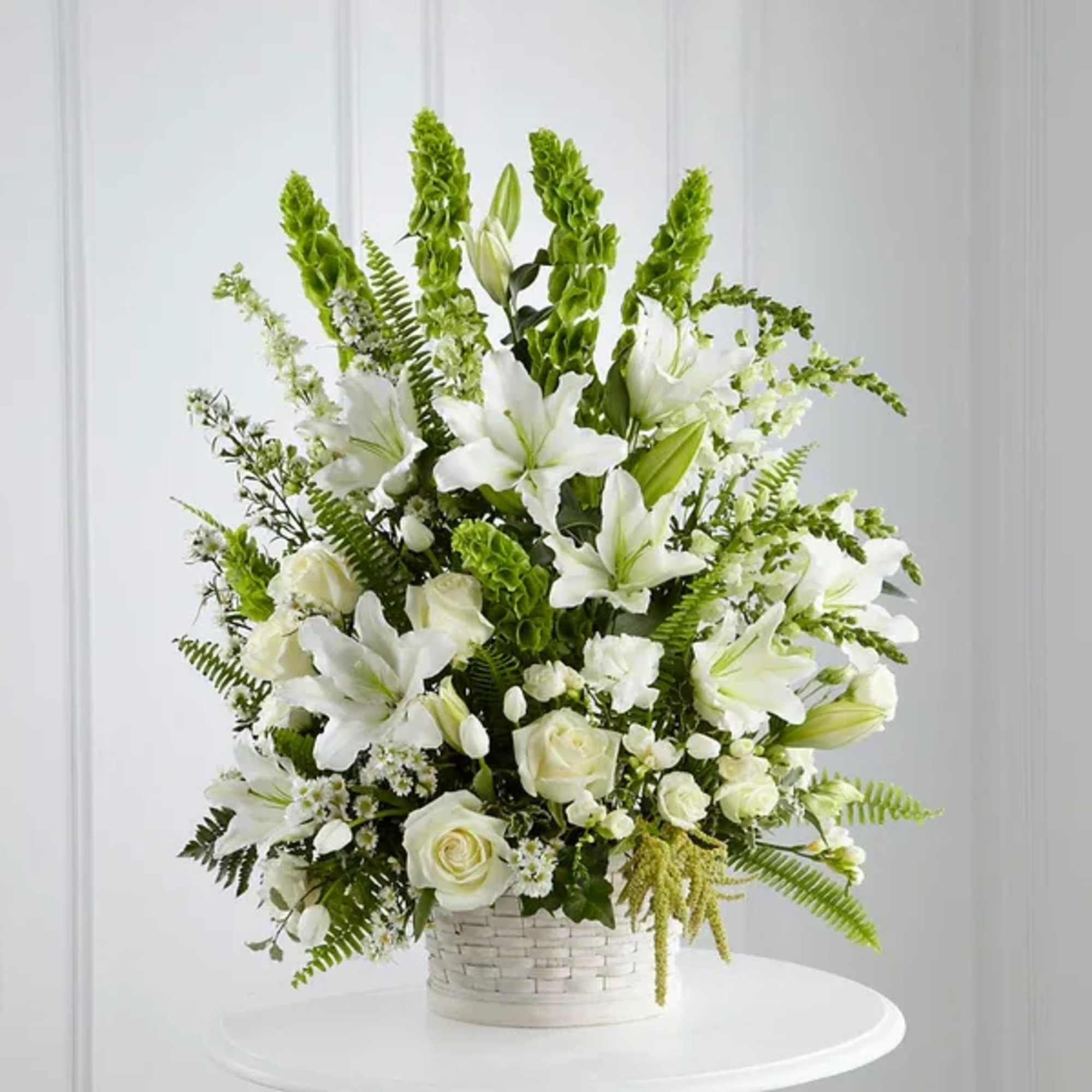 White lilies and roses in a white basket arrangement