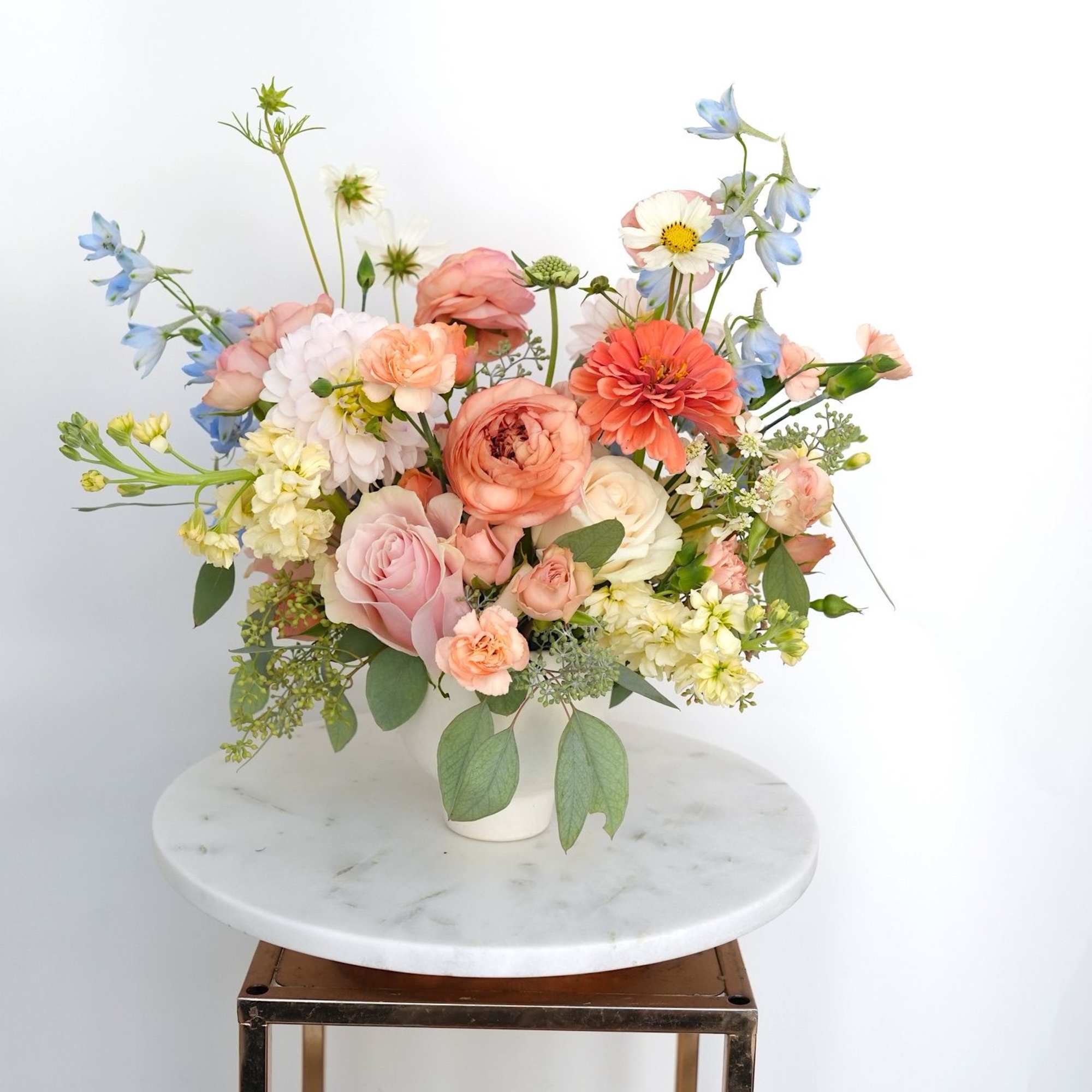 Pastel mixed flower arrangement in a white vase on a round table